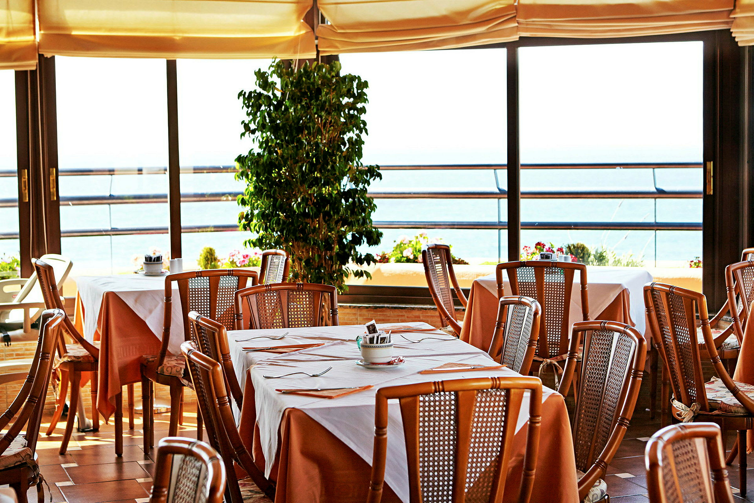 Restaurant med oppdekkede bord og utsikt mot havet. (AI-generert tekst)