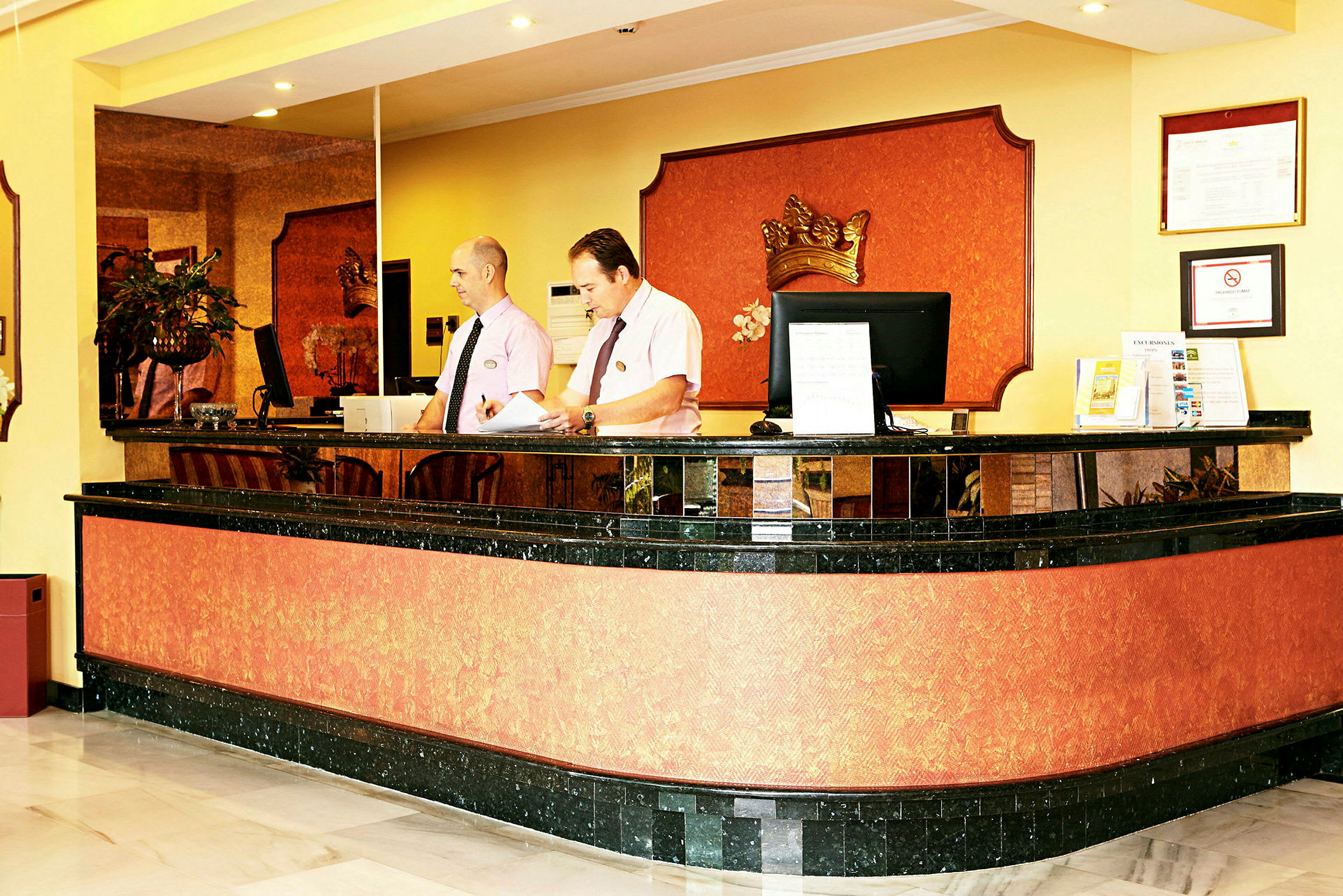 Resepsjon i en hotellobby med en svart og oransje fargedesign og dekorasjoner. (AI-generert tekst)