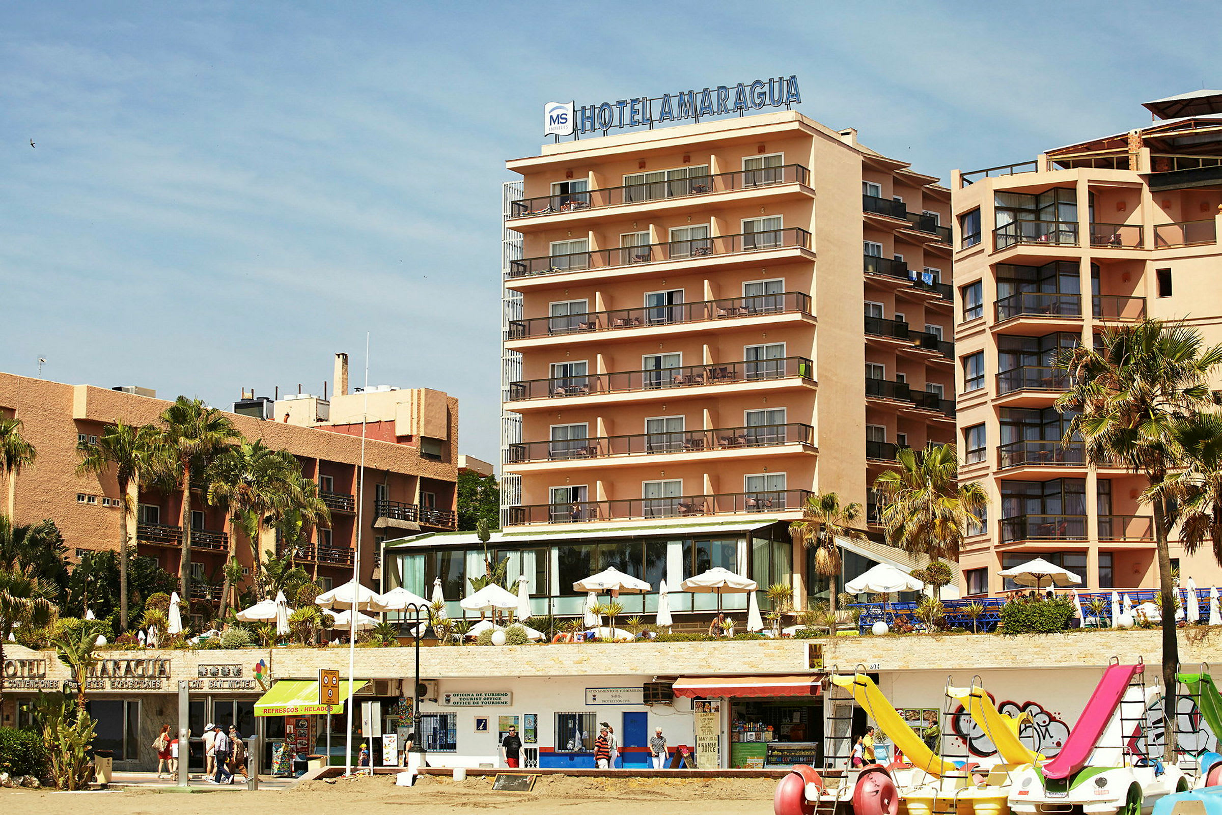 Et hotell ved stranden med parasoller og utsikt over havet. (AI-generert tekst)