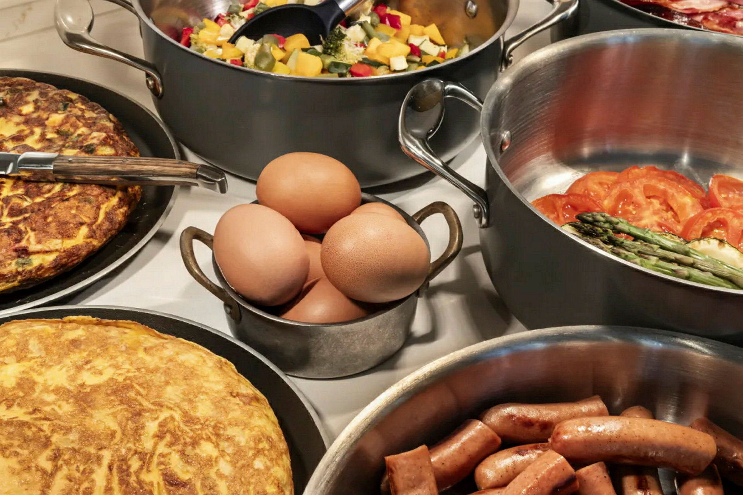 Ulike retter, inkludert omelett, pølser, egg og grønnsaker, arrangert på et bord. (AI-generert tekst)