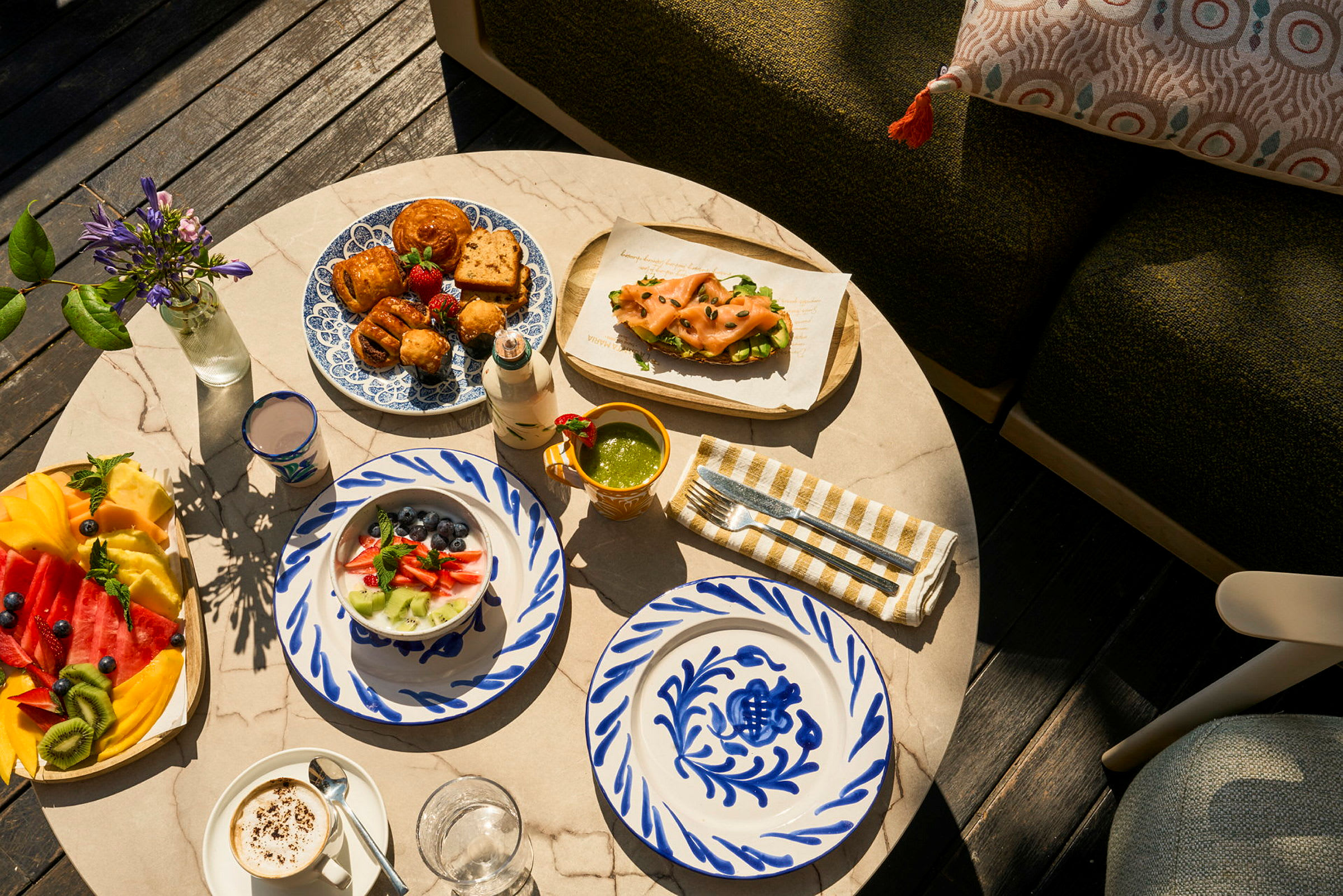 Et marmorbord med et utvalg av fargerike retter, frokost og dekorative tallerkener, samt friske blomster. (AI-generert tekst)