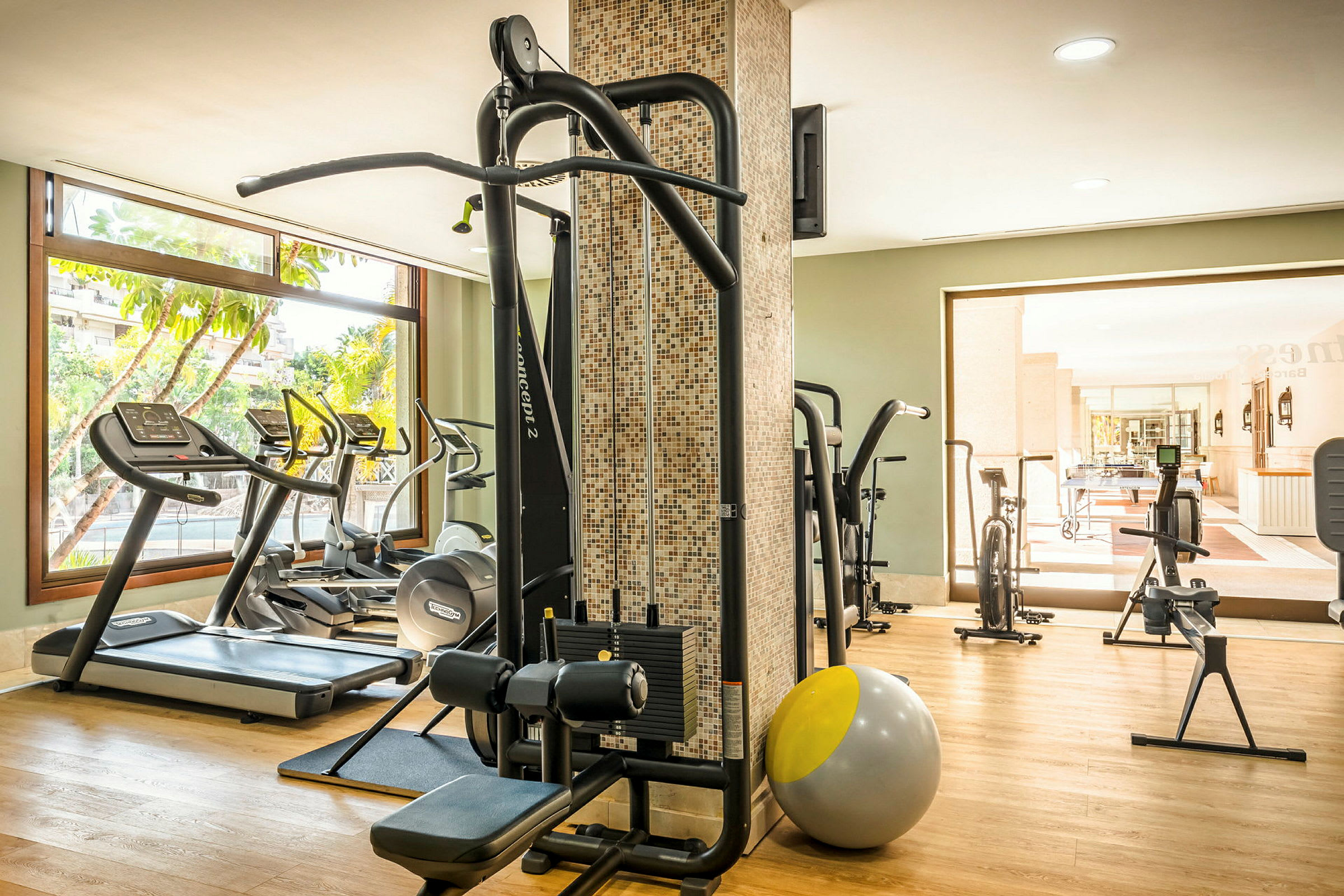Et moderne treningsstudio med treningsutstyr, inkludert tredemøller, styrketreningsmaskiner og pilatesball. (AI-generert tekst)