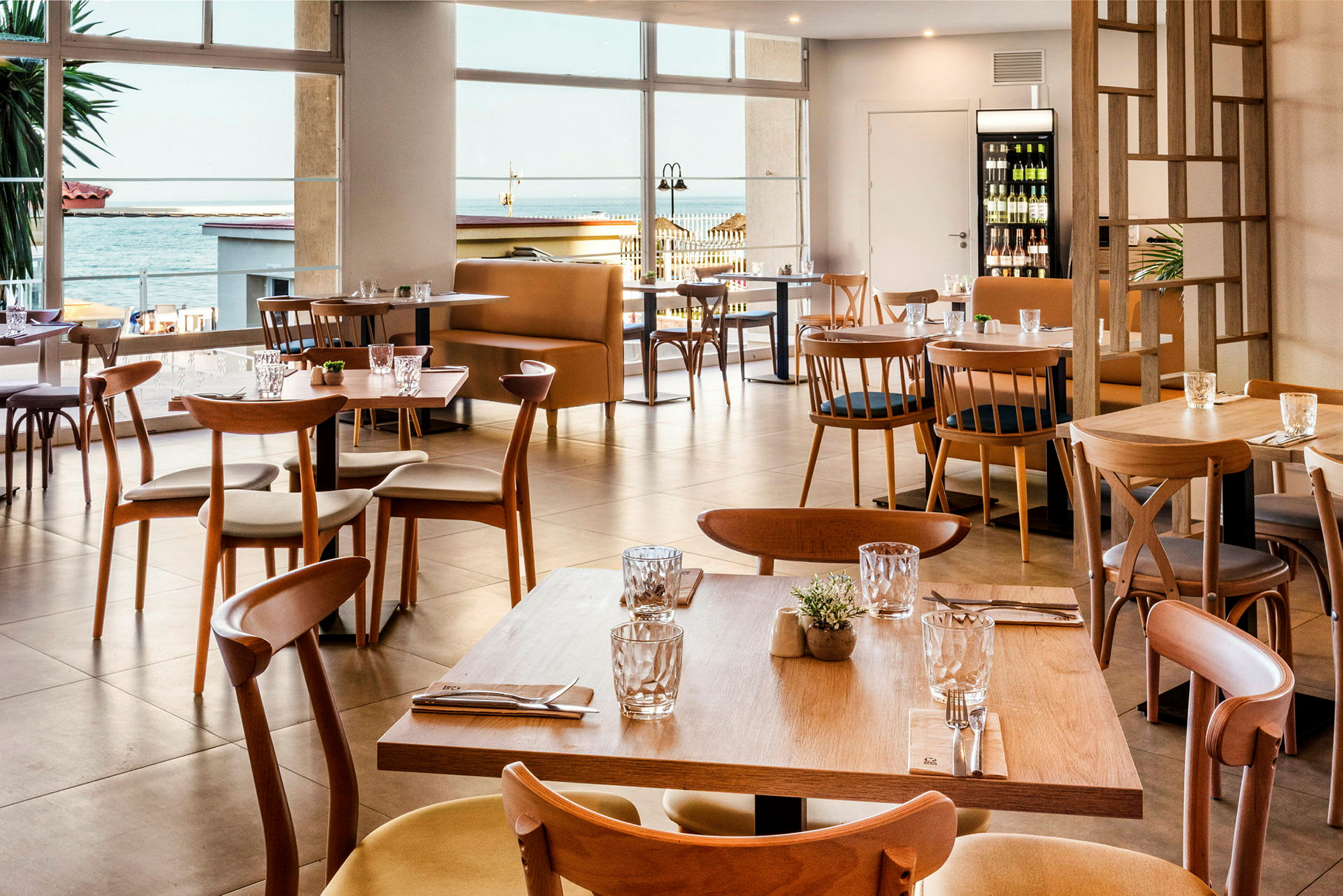 Moderne bord og stoler i tre i en restaurant med sjøutsikt. (AI-generert tekst)
