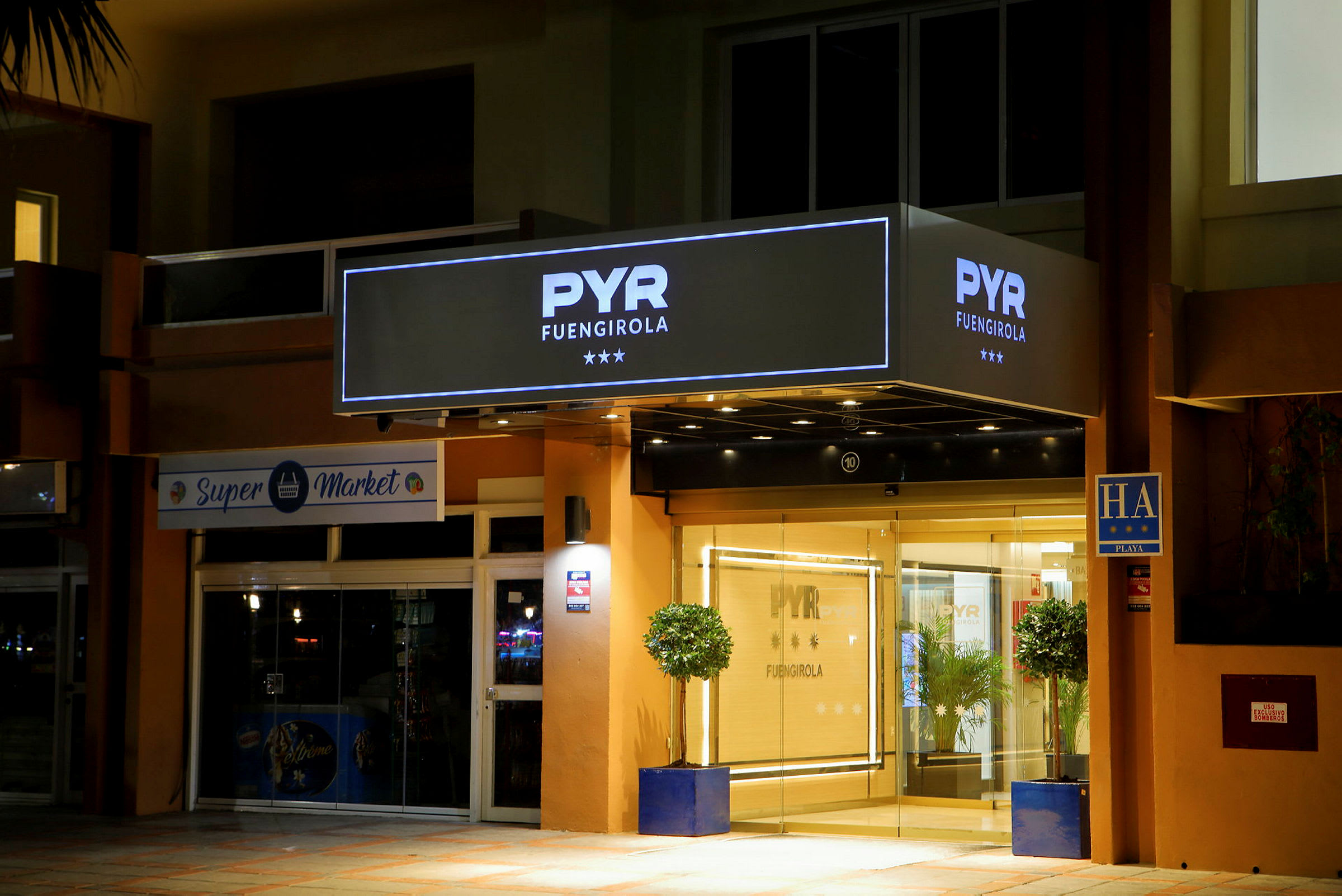 Hotellinngangen til PYR Fuengirola med lys og skilt. (AI-generert tekst)