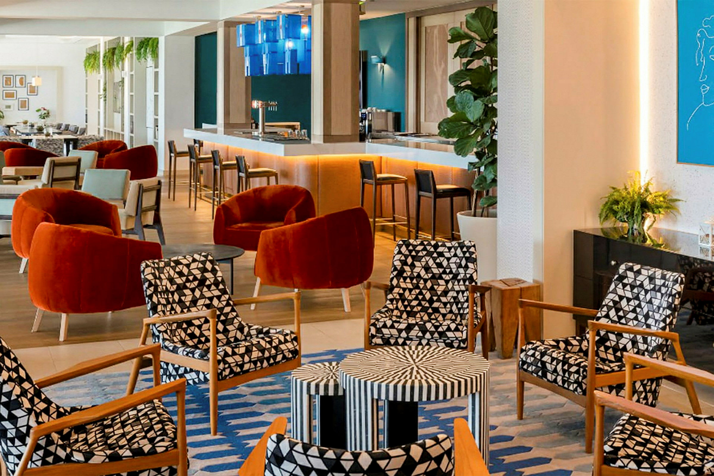 En moderne lounge med komfortable stoler i røde og mønstrede farger, et barområde og veggdekorasjoner. (AI-generert tekst)