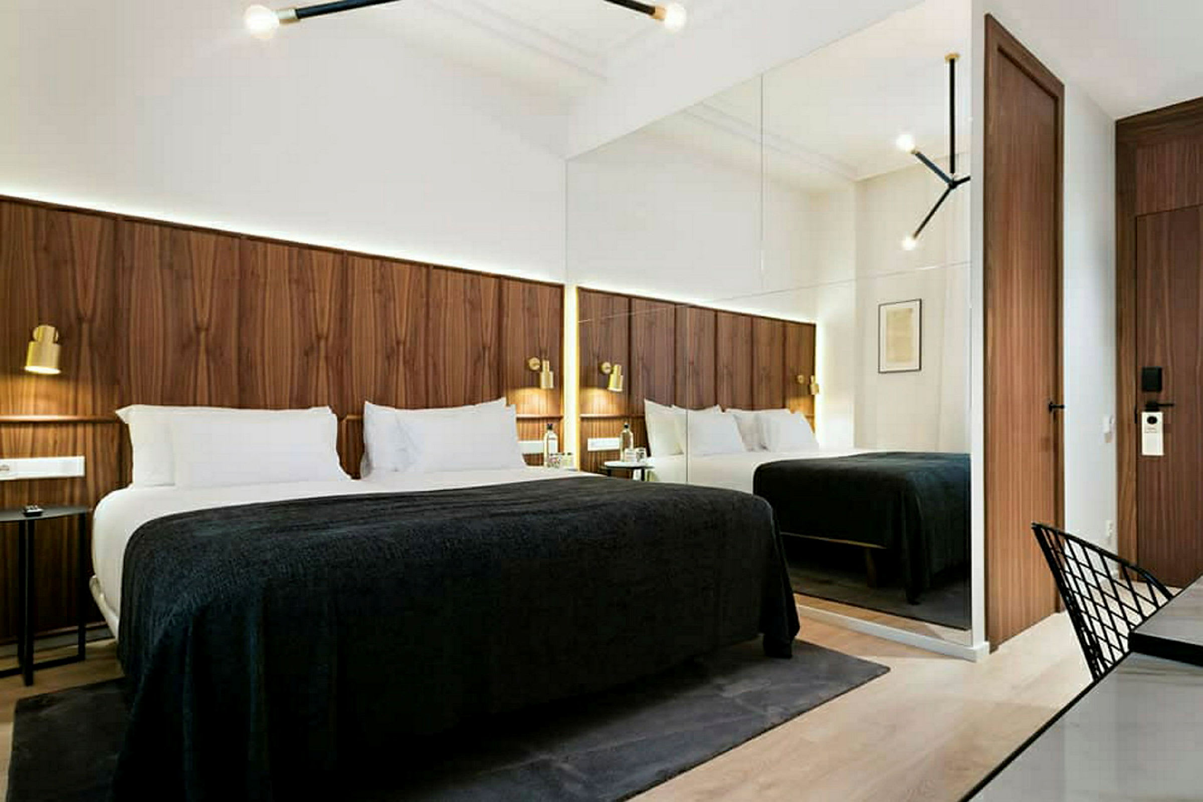 Et moderne hotellrom med en stor seng, trepaneler på veggen og speil som gir rommet en romfølelse. (AI-generert tekst)