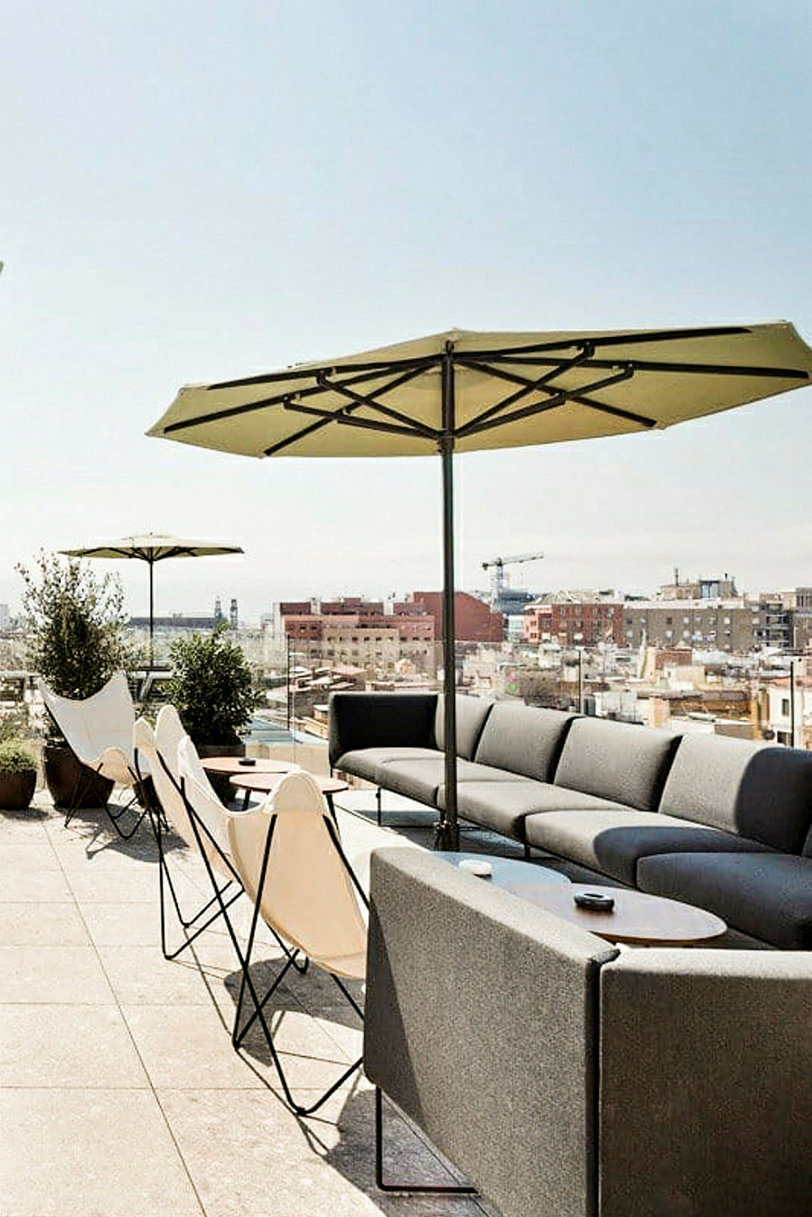 Bilde av en terrasse med sittemøbler, parasoller og utsikt over byens tak. (AI-generert tekst)