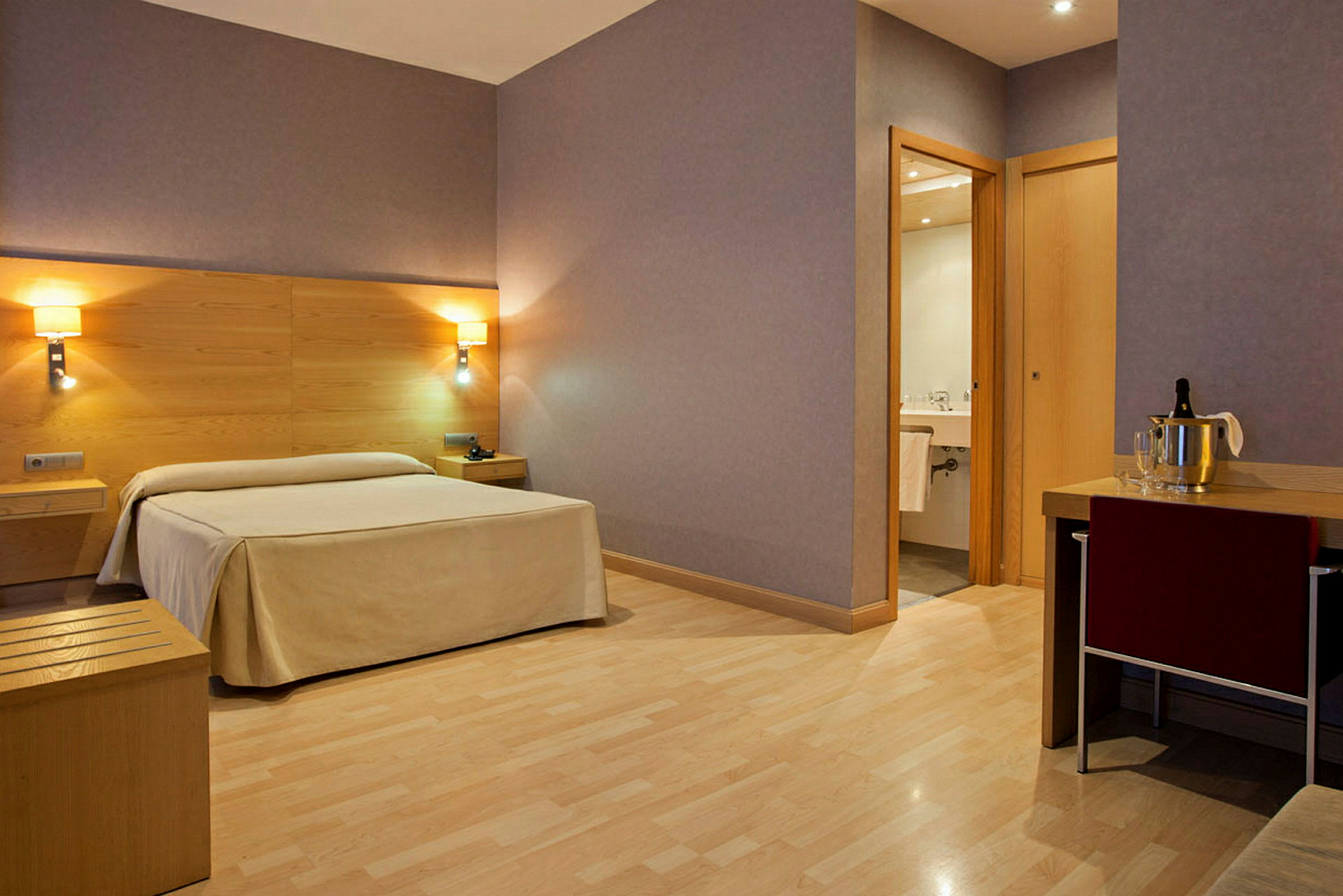Hotellrom med en seng, nattbord, et skrivebord og et bad. (AI-generert tekst)