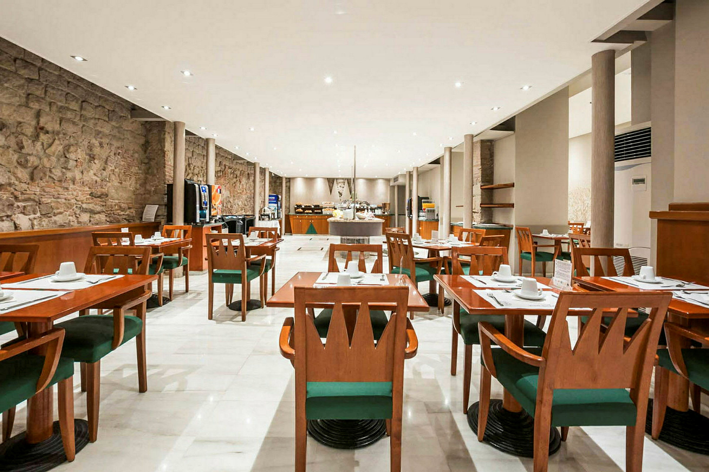 Et romslig restaurantområde med tremøbler, hvite duker, grønne stoler og en moderne innredning. (AI-generert tekst)
