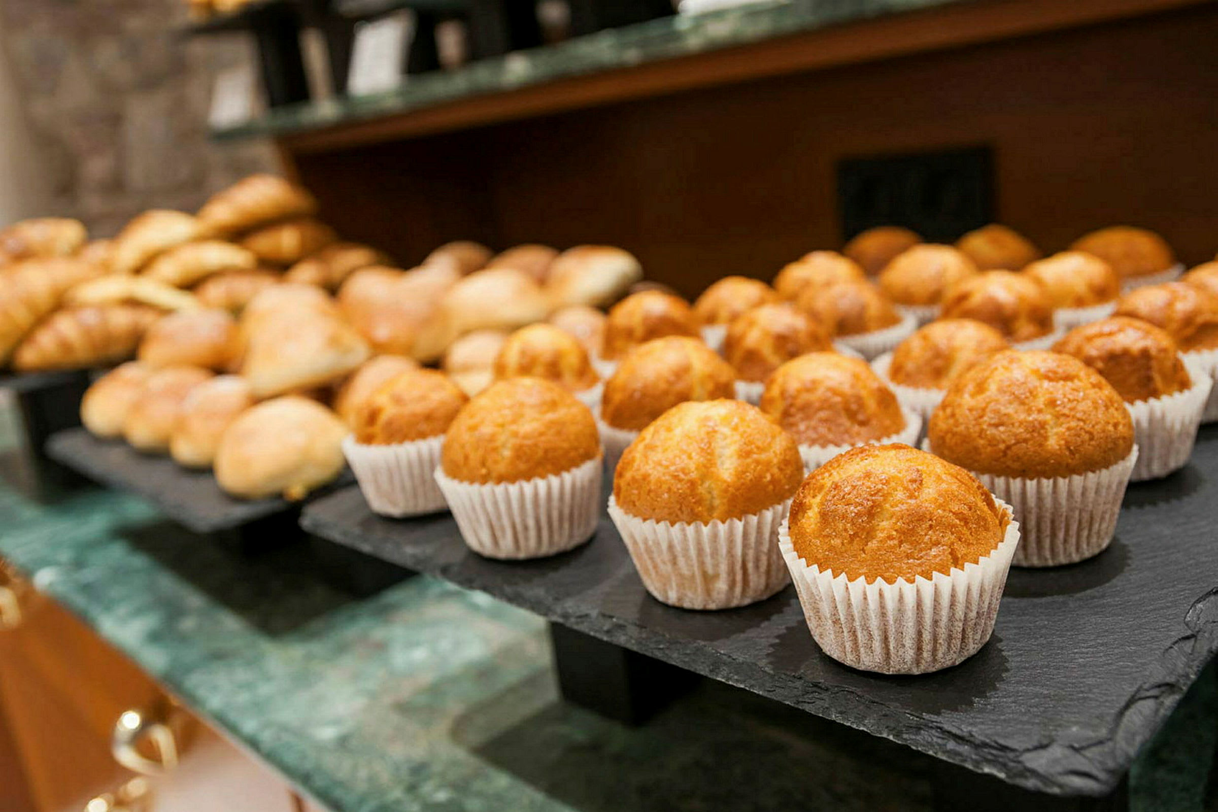 Et nærbilde av et fat med muffins og andre bakverk på et bord. (AI-generert tekst)