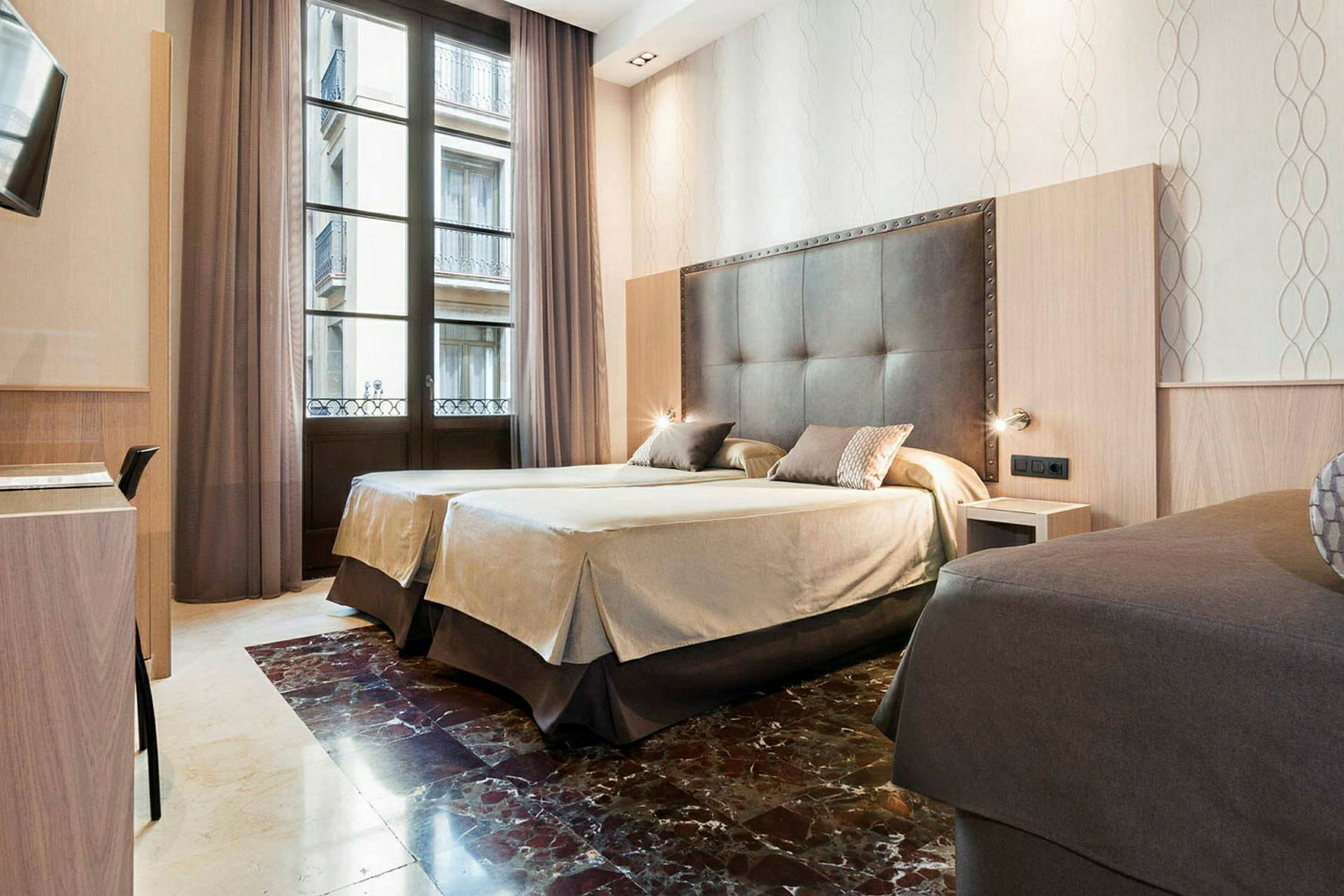 Et hotellrom med to redde senger, store vinduer med gardiner og en elegant innredning. (AI-generert tekst)