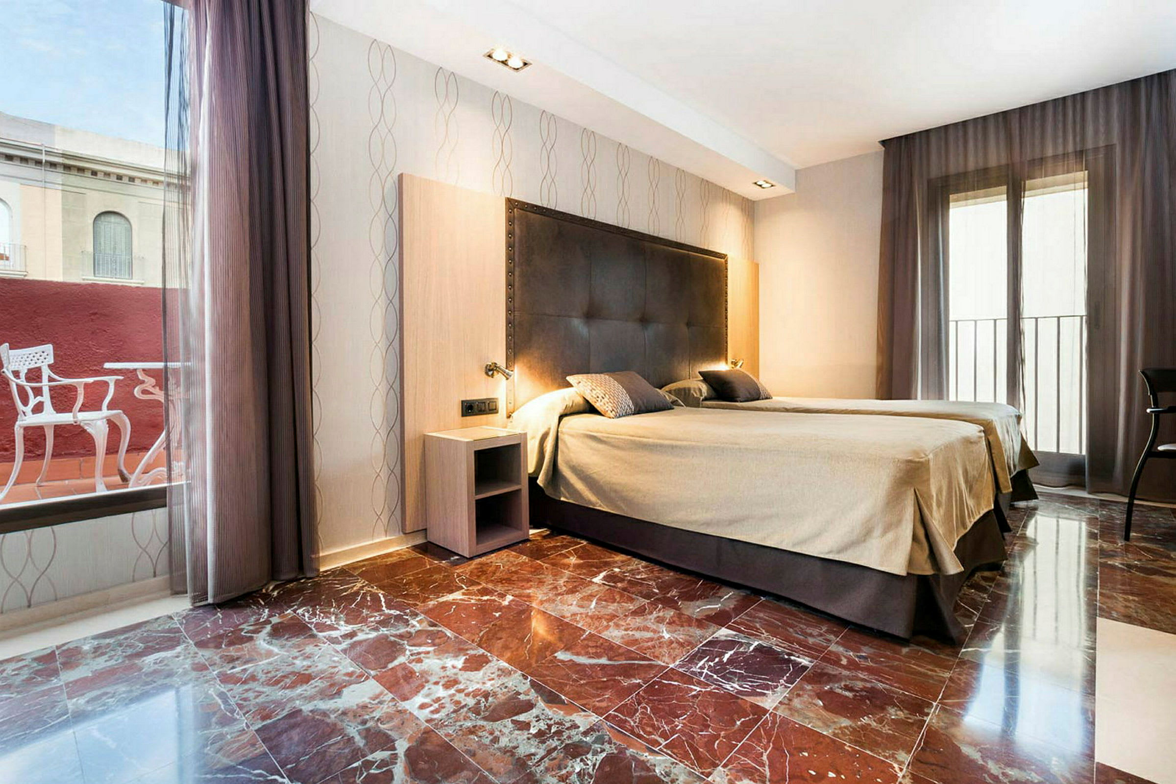 Et hotellrom med to enkeltsenger, marmorgulv og store vinduer med gardiner. (AI-generert tekst)