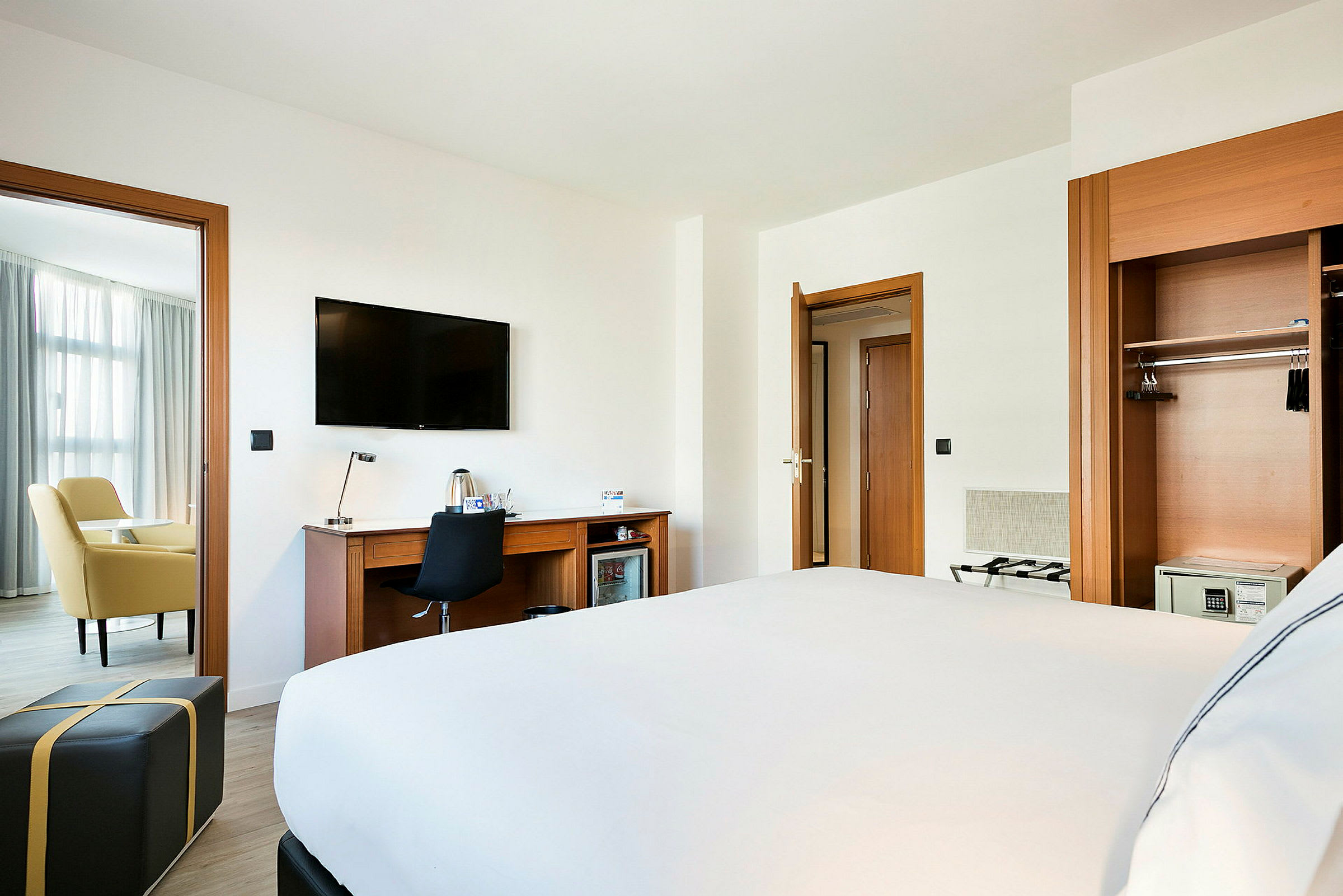 Hotellrom med en seng, skrivebord, TV og sittegruppe. (AI-generert tekst)