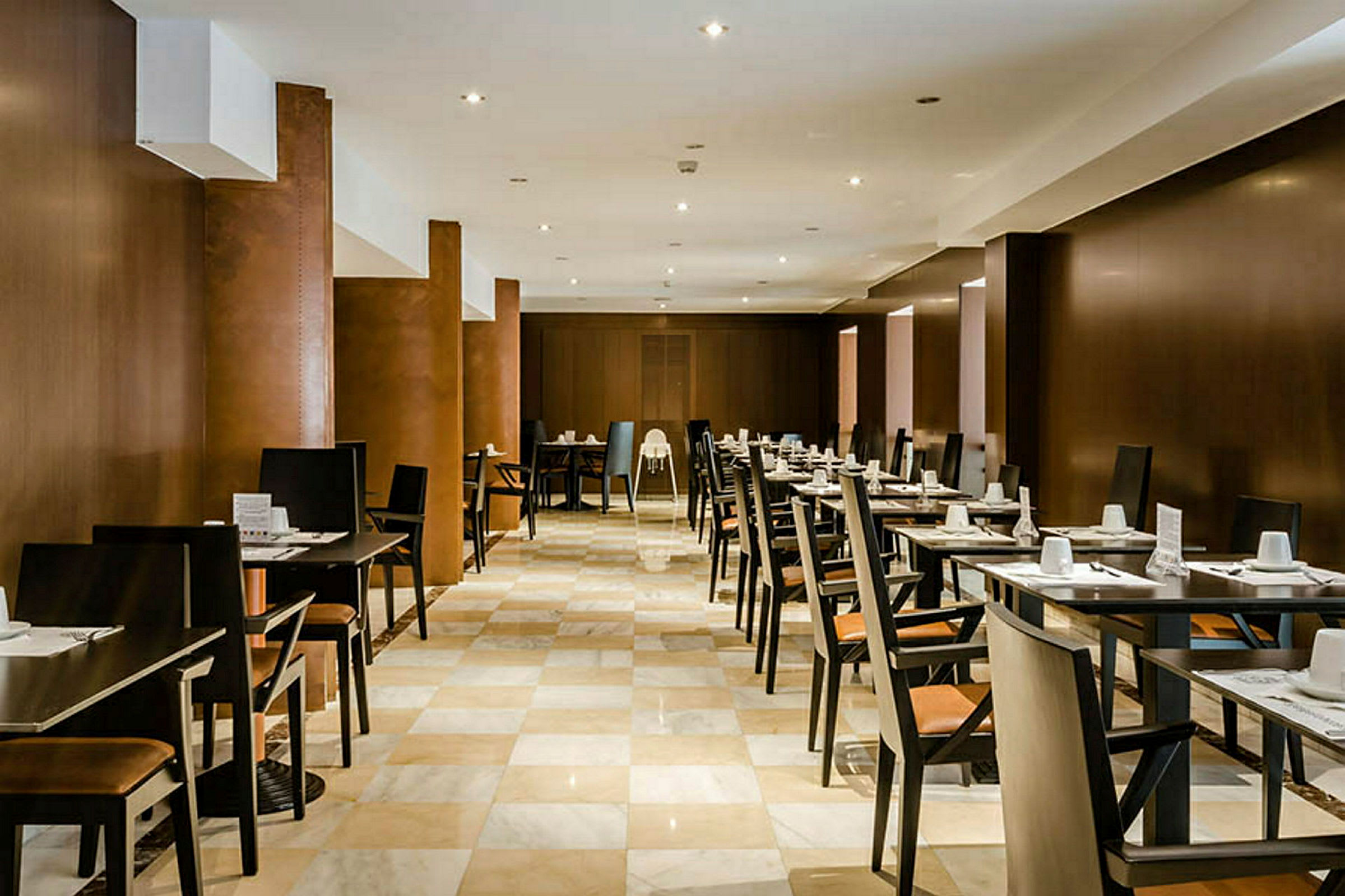 Et restaurantområde med rekker av bord og stoler, dekket for gjester. (AI-generert tekst)
