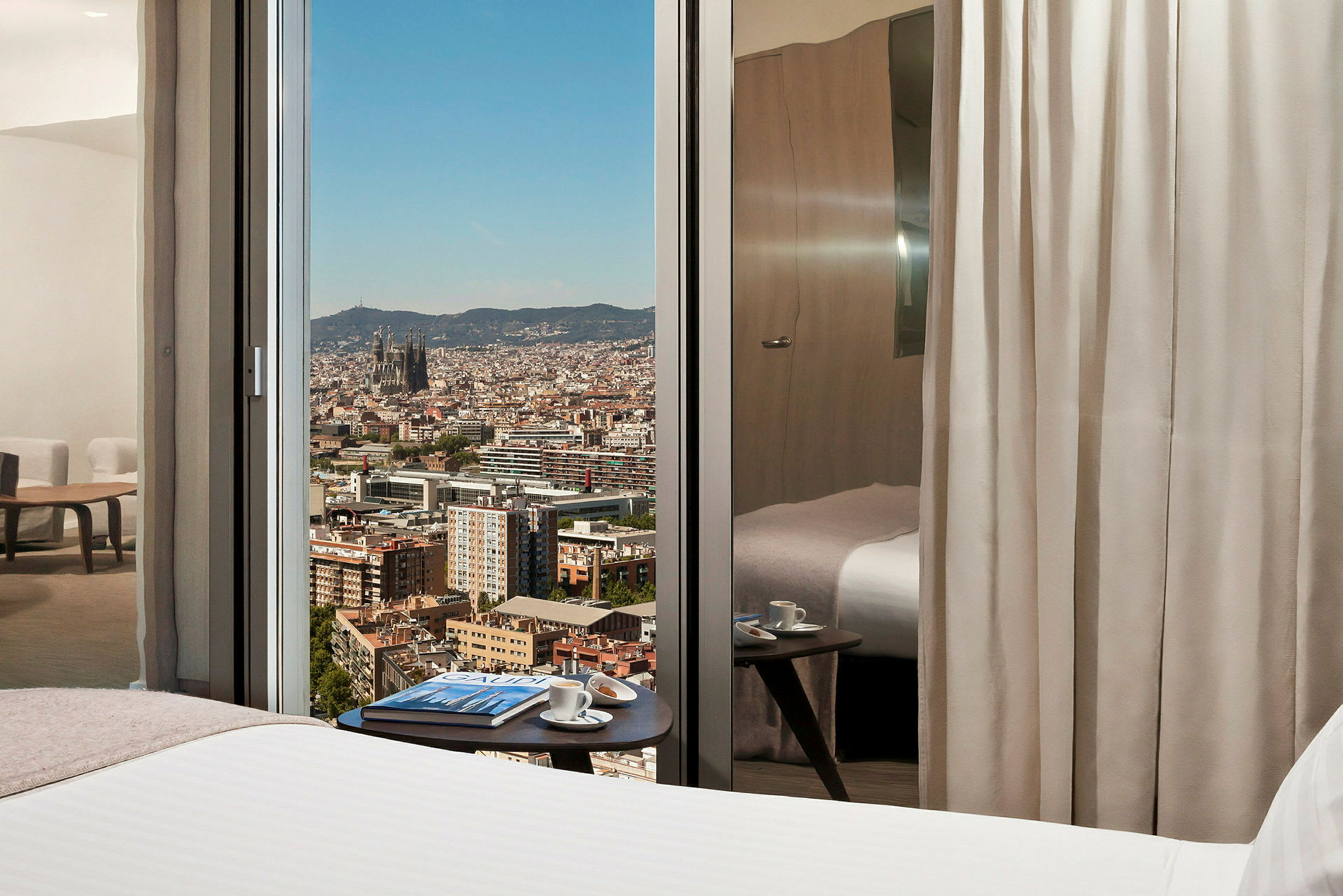 Hotellrom med utsikt over en by gjennom glassvinduer. (AI-generert tekst)