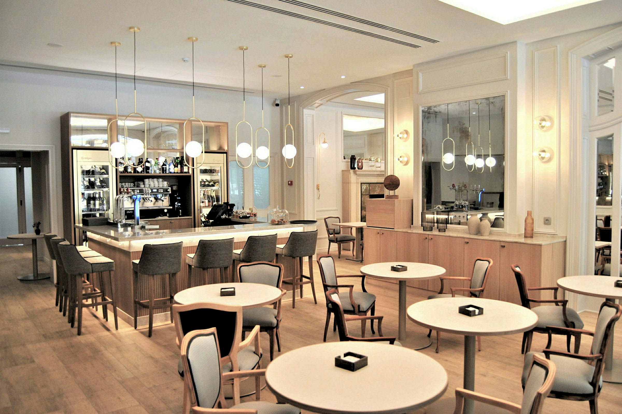 En elegant bar med et stort avrundet bord og stoler i et lyst, moderne interiør. (AI-generert tekst)