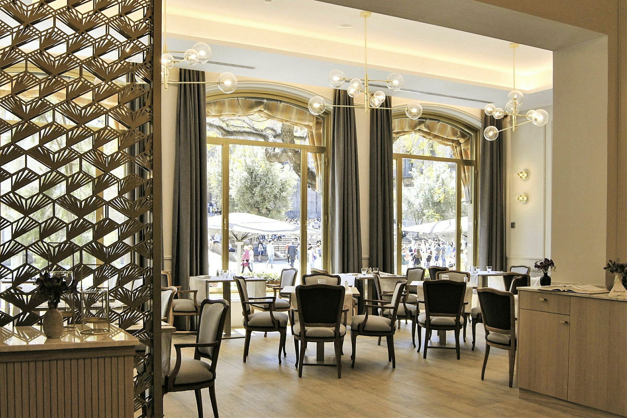Interiør av en restaurant med store vinduer og elegante møbler. (AI-generert tekst)
