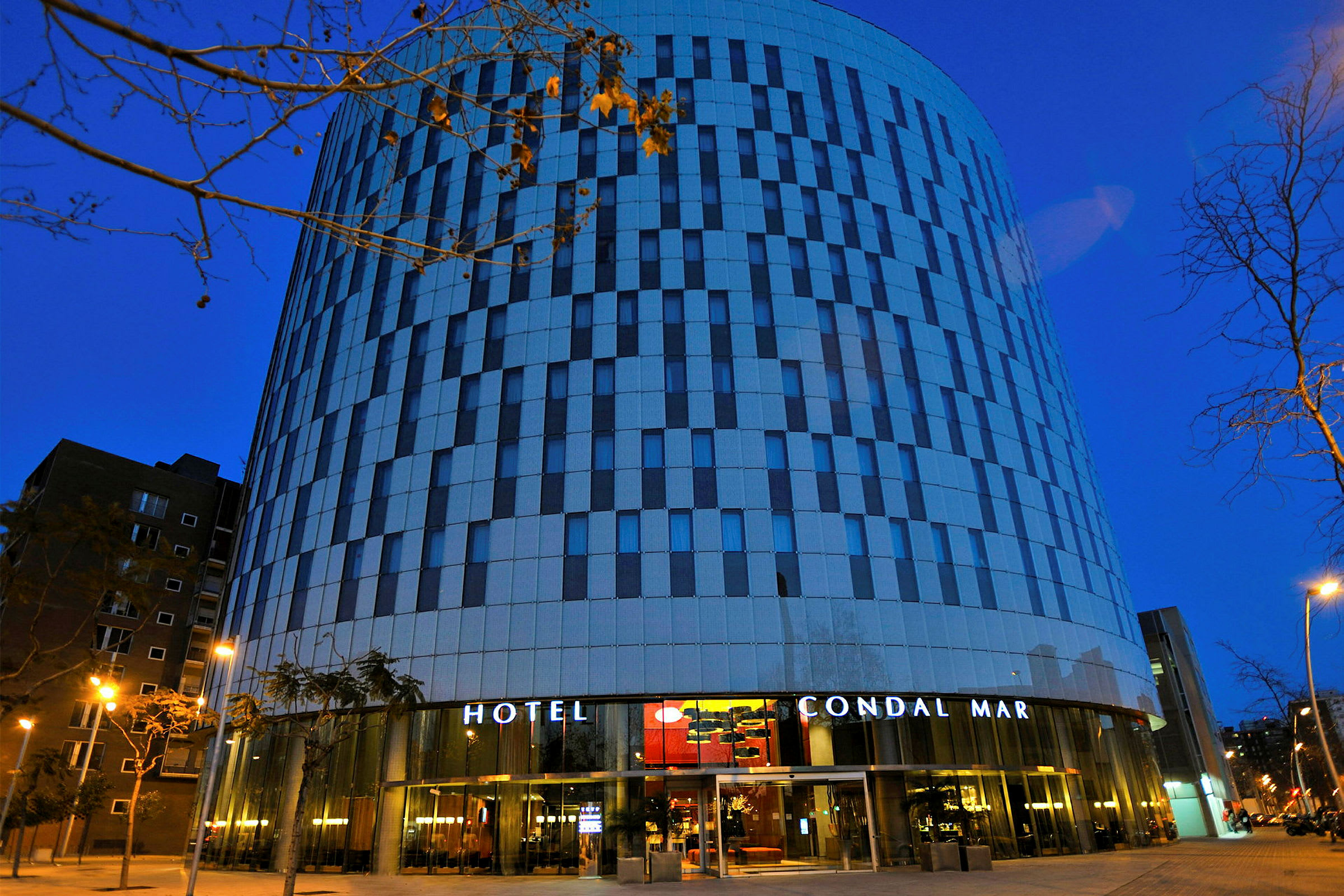 Et hotell med moderne arkitektur og en fasade med striper av glass og betong fotografert i skumringen. (AI-generert tekst)