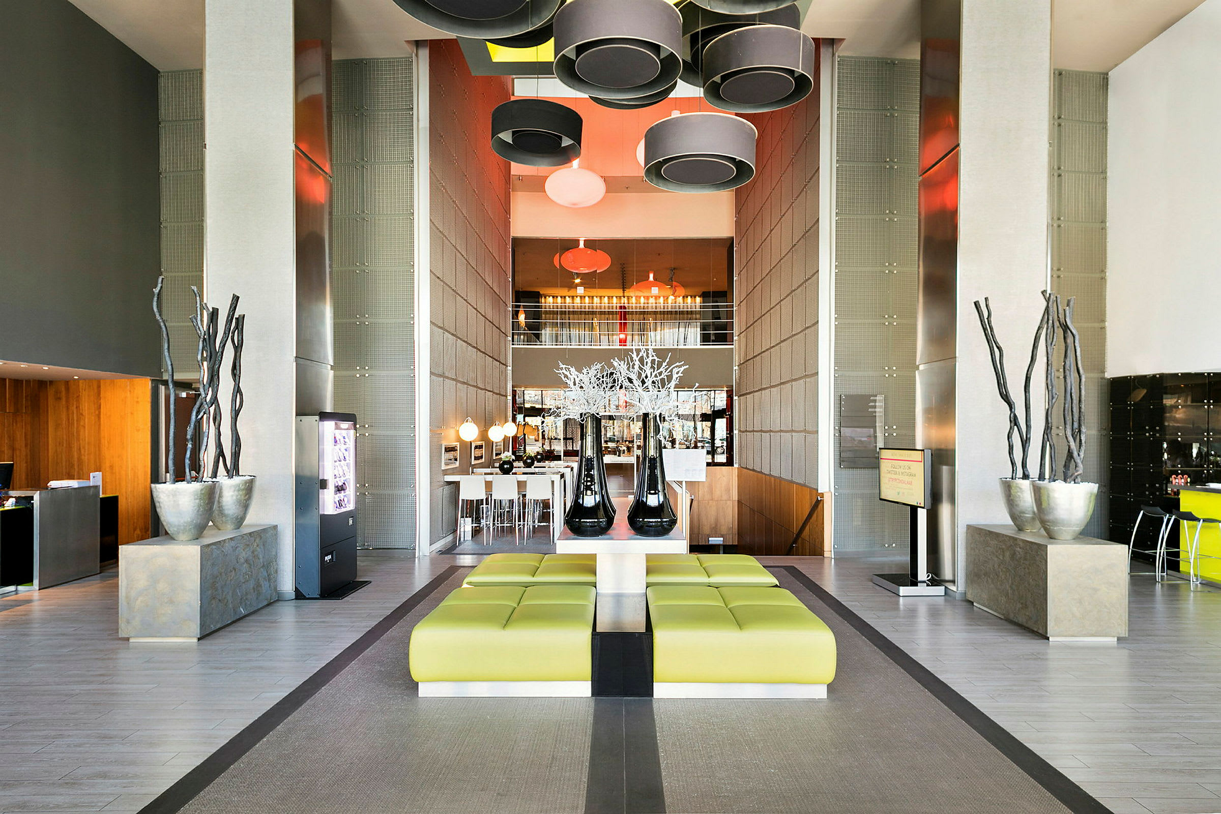 Moderne hotellobby med grønne sitteplasser, dekorative elementer og hengende lamper. (AI-generert tekst)
