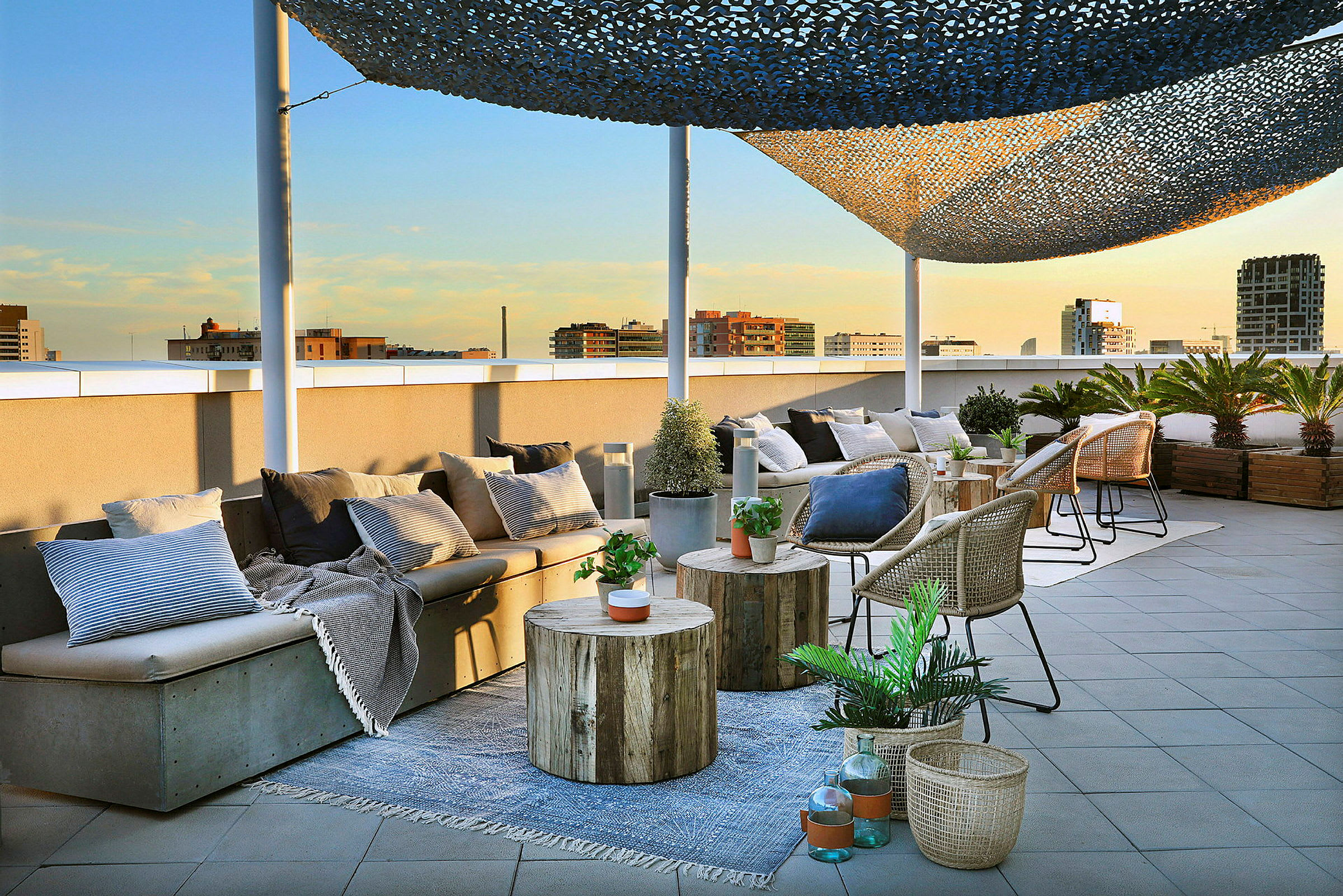 En takterrasse med sittemøbler, bord og kurver dekorert med planter og puter er avbildet. (AI-generert tekst)