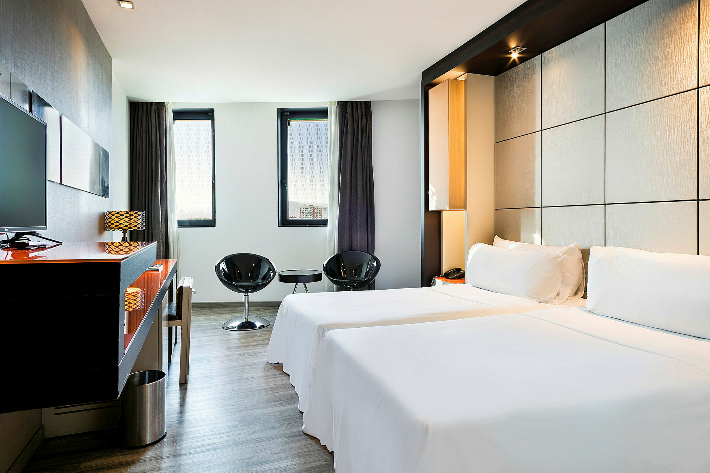 Et elegant hotellrom med to enkeltsenger, minimalistisk innredning og store vinduer som slipper inn naturlig lys. (AI-generert tekst)