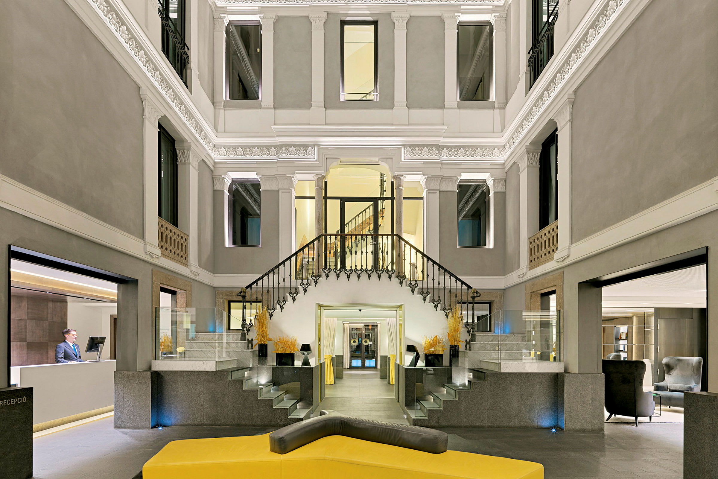 En elegant hotellobby med trapp i midten og en resepsjonsdisk til venstre. Designet er moderne med klassiske detaljer. (AI-generert tekst)