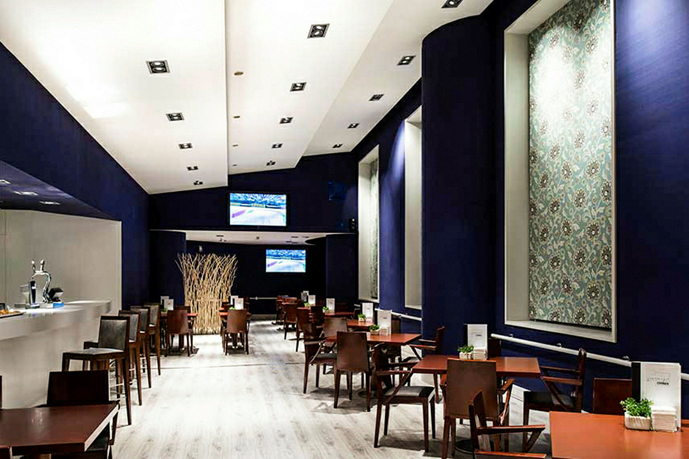 En moderne restaurant eller kafé med tremøbler og mørke dekorer. Den viser bord og stoler arrangert på rader under et sterkt opplyst tak. (AI-generert tekst)