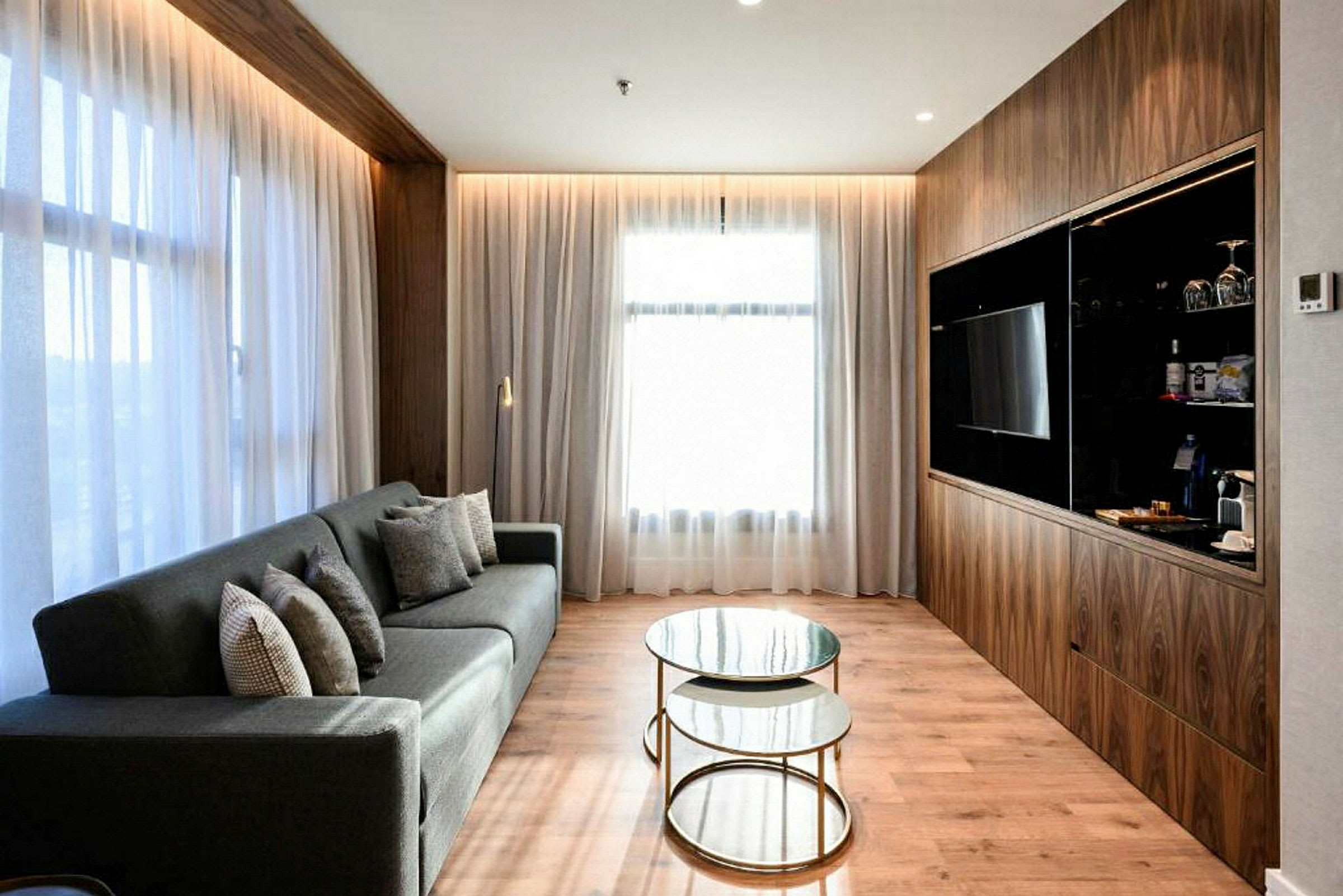 En moderne stue med sofa, glassbord og TV ved trepanel. (AI-generert tekst)