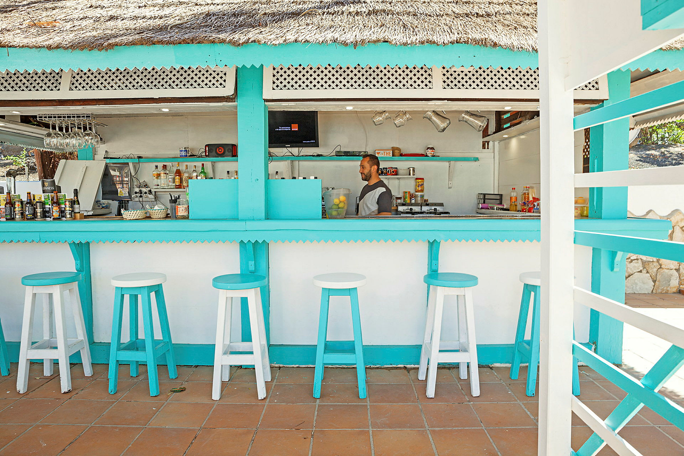 En strandbar med turkise detaljer og hvite barkrakker. (AI-generert tekst)