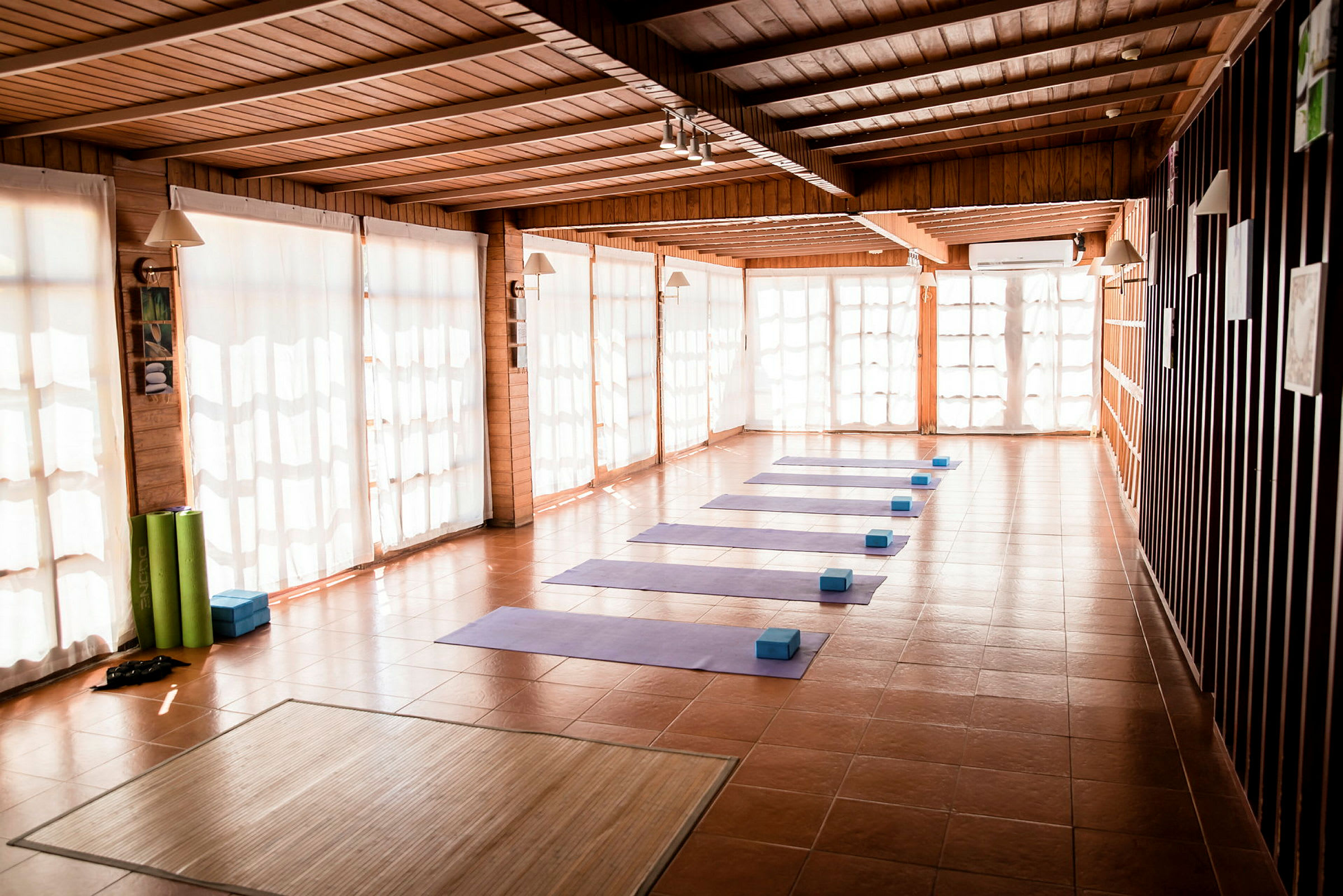 Et solbelyst rom med yogamatter og blokker arrangert på gulvet. (AI-generert tekst)