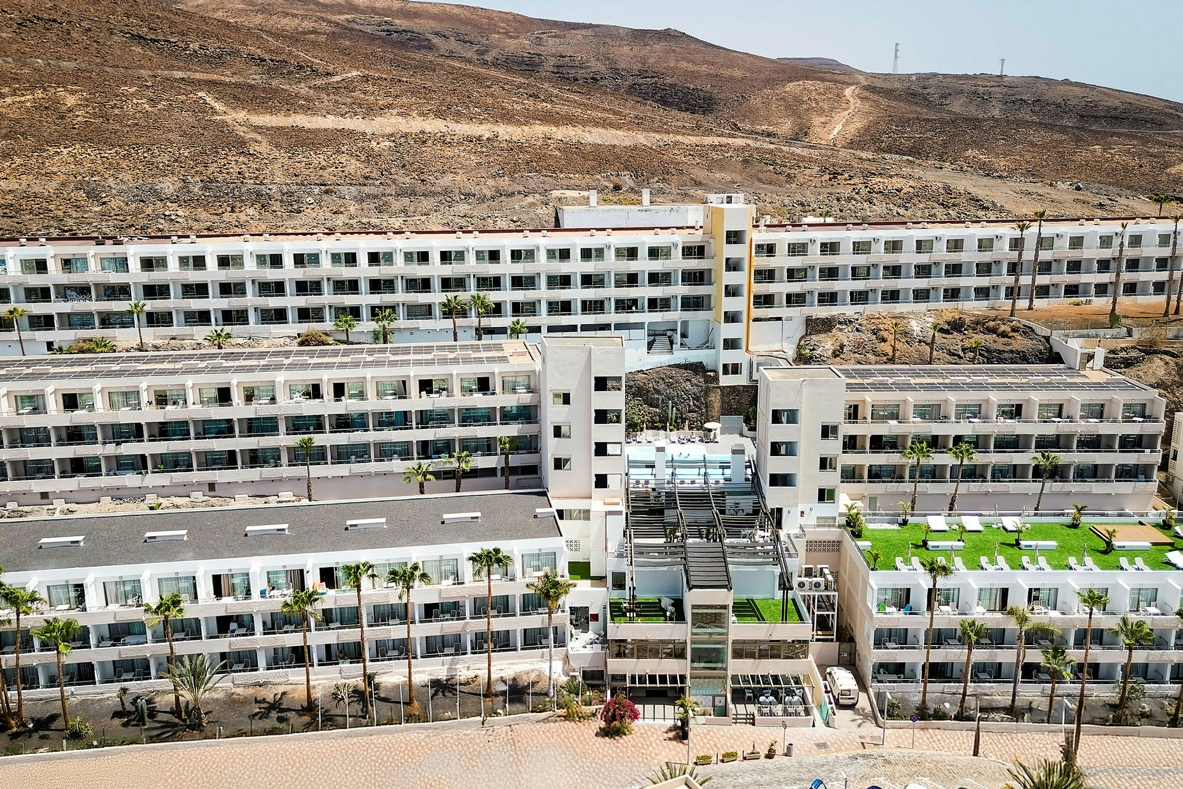 Et stort hotellkompleks omgitt av et tørt, fjellrikt landskap. (AI-generert tekst)