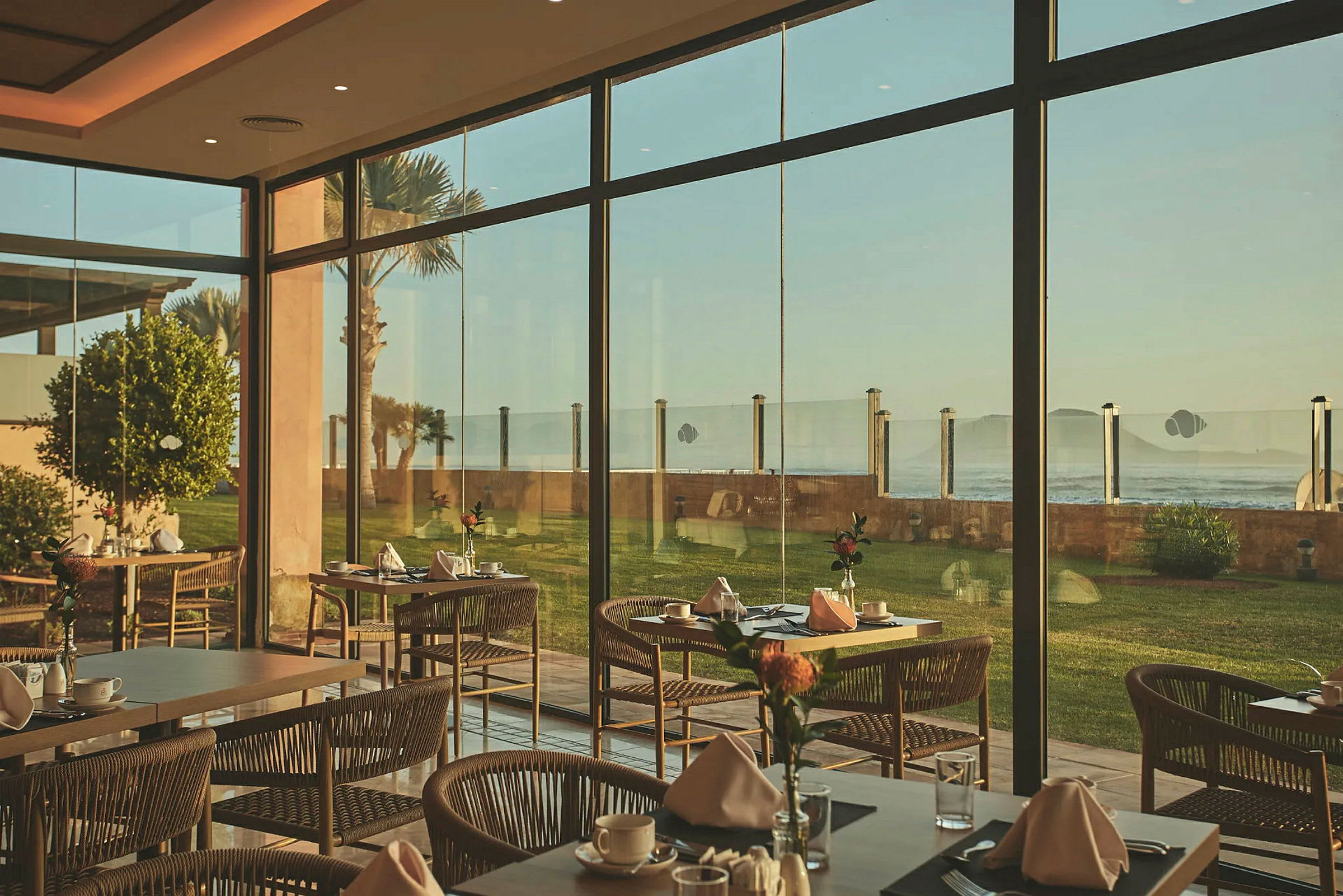 Restaurant med dekkede bord og store vinduer med utsikt over havet. (AI-generert tekst)