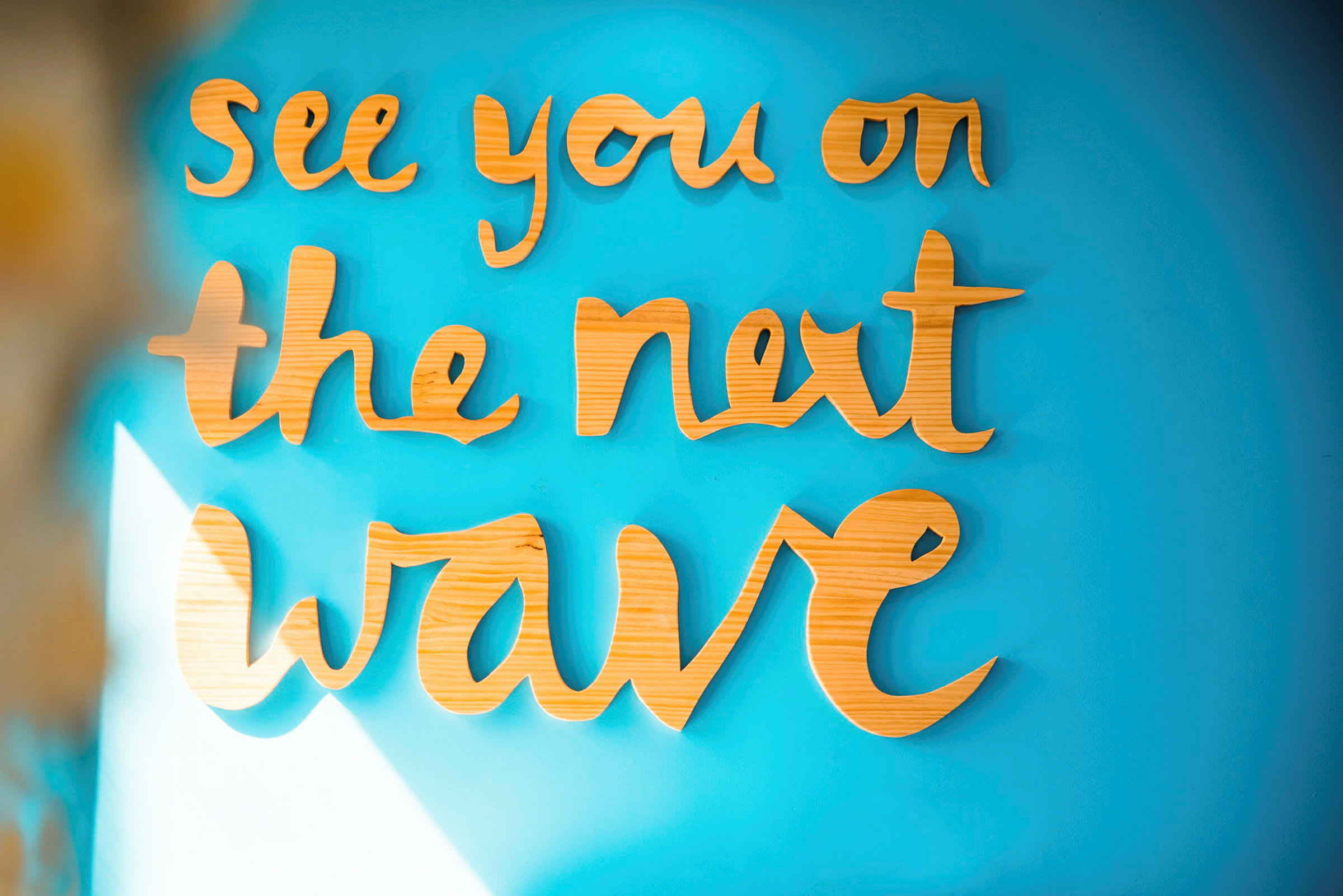Tekst i tremateriale: "See you on the next wave" på en blå vegg. (AI-generert tekst)