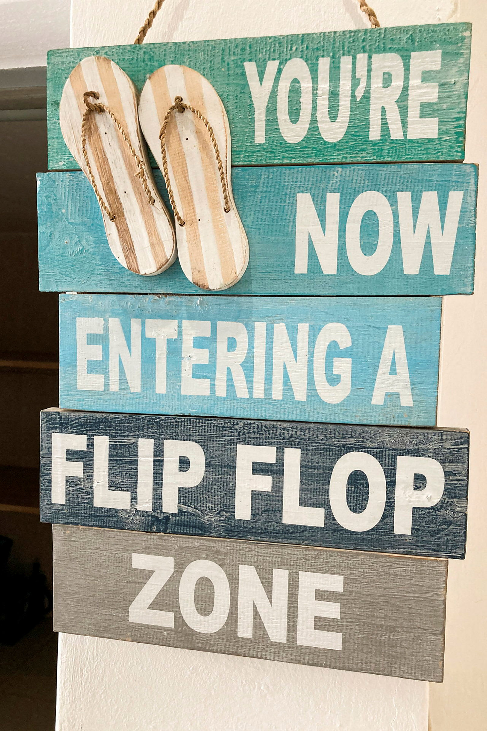 Et skilt med teksten 'You're now entering a flip flop zone' og to hengende sandaler øverst. (AI-generert tekst)
