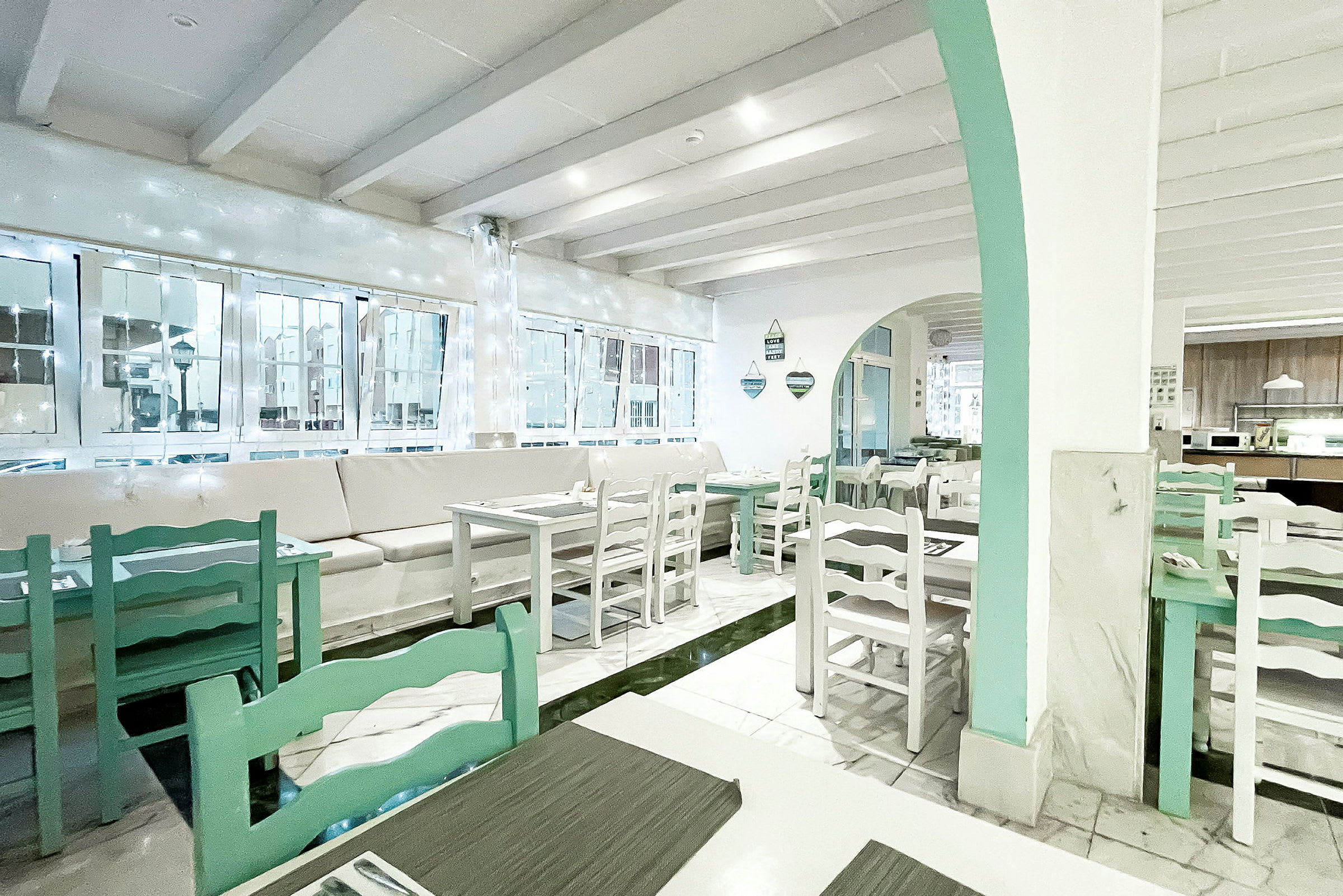 En lys og luftig kafé eller restaurant med hvite vegger og lysegrønne møbler. (AI-generert tekst)