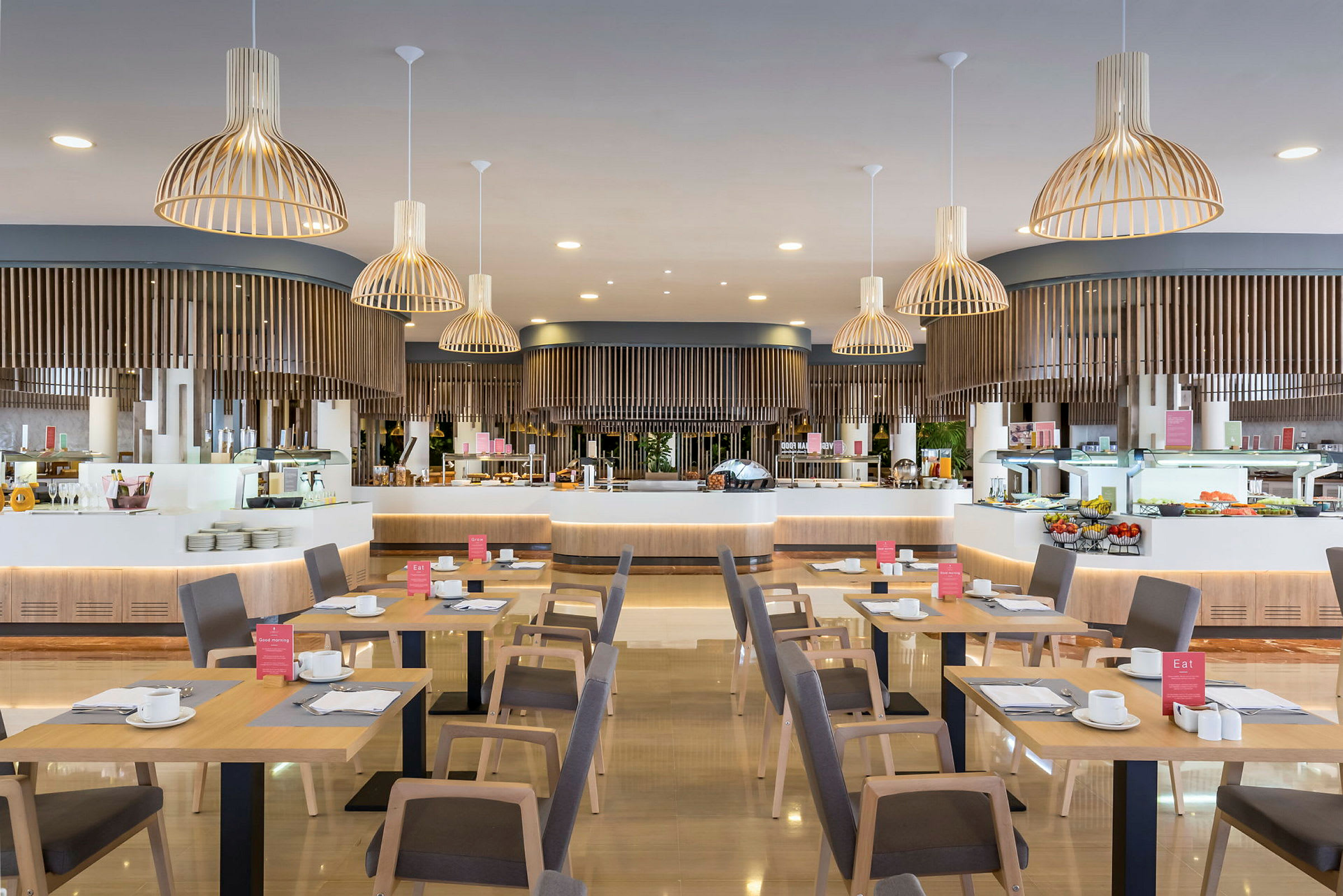 En restaurant med trebord og stoler, serveringsområde i bakgrunnen med lamper hengende fra taket. (AI-generert tekst)