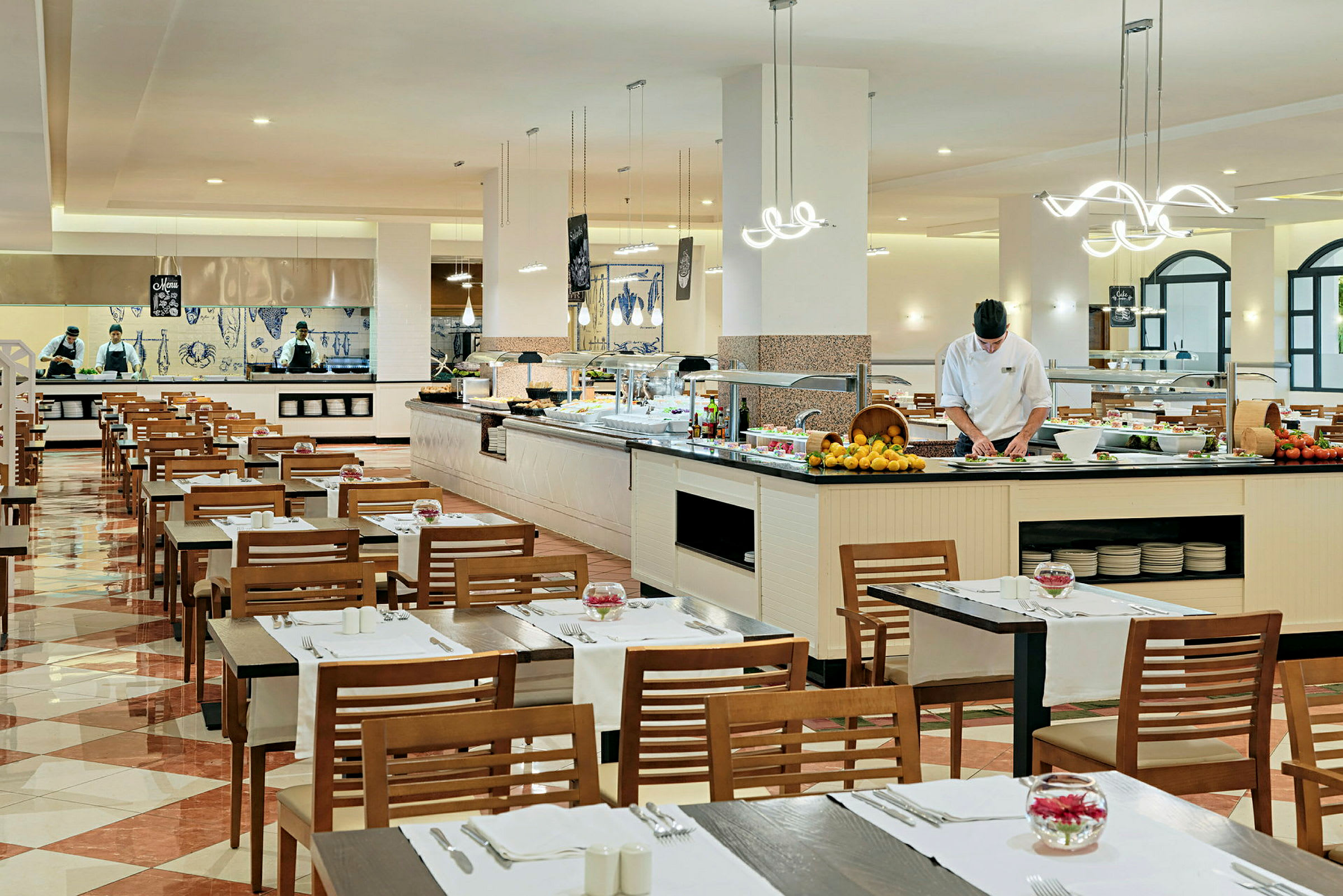 Restaurant med dekkede bord og en buffé. Personale arbeider ved matstasjonen. (AI-generert tekst)
