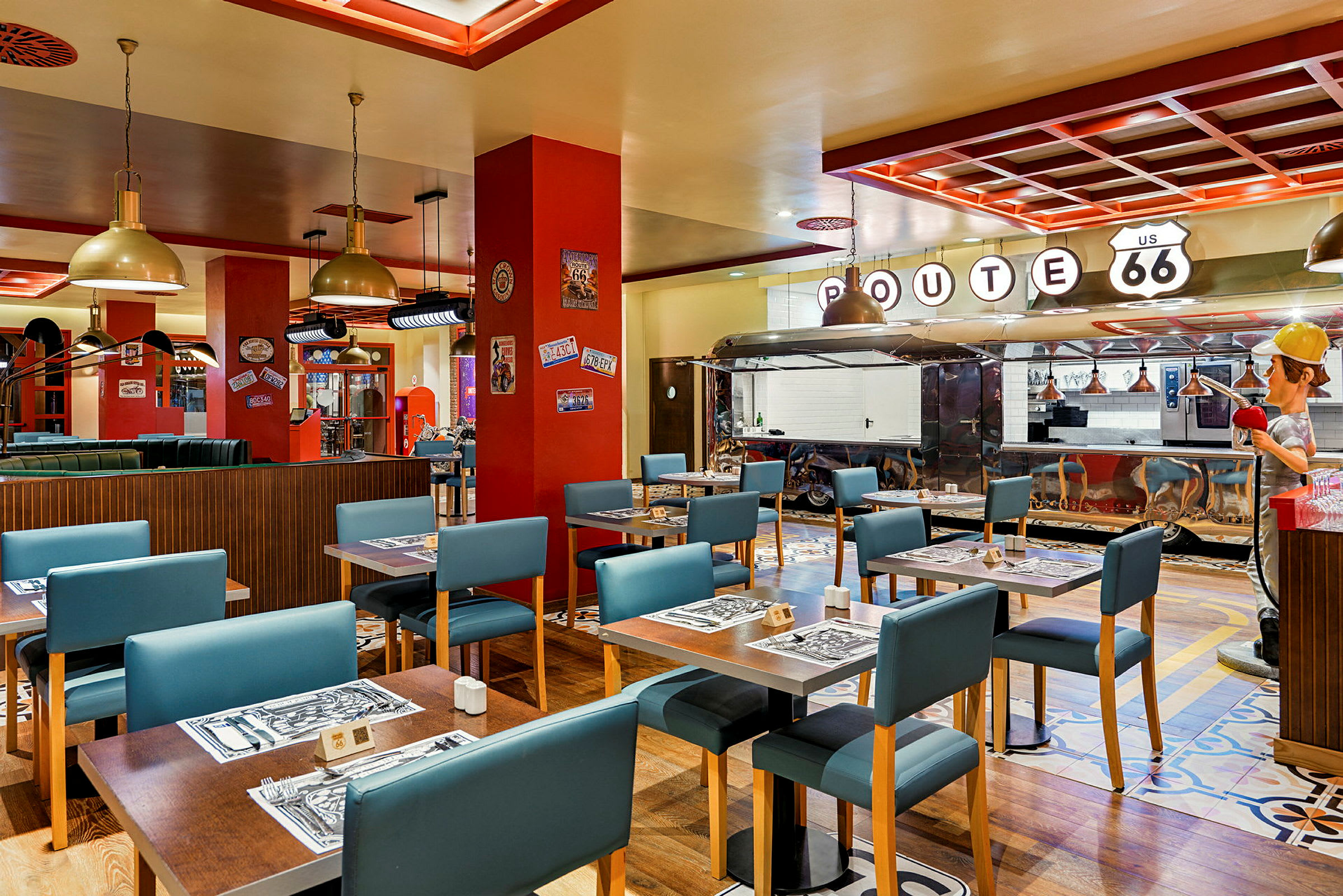 En restaurant innredet i amerikansk Route 66-stil med bord, blå stoler og en serveringsdisk. (AI-generert tekst)