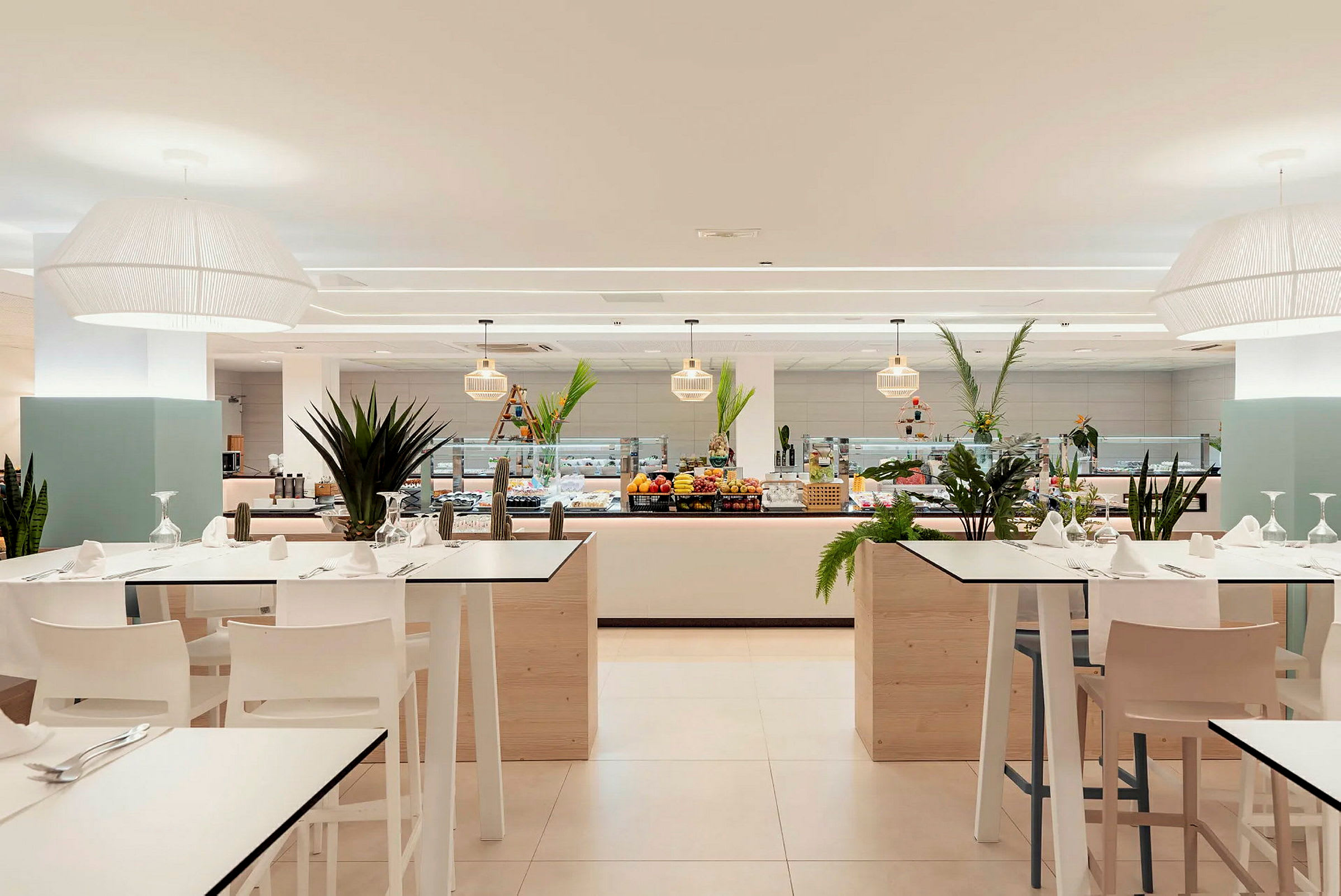 Interiør av en restaurant med dekkede bord og en buffet med fargerike ingredienser og grønne planter. (AI-generert tekst)