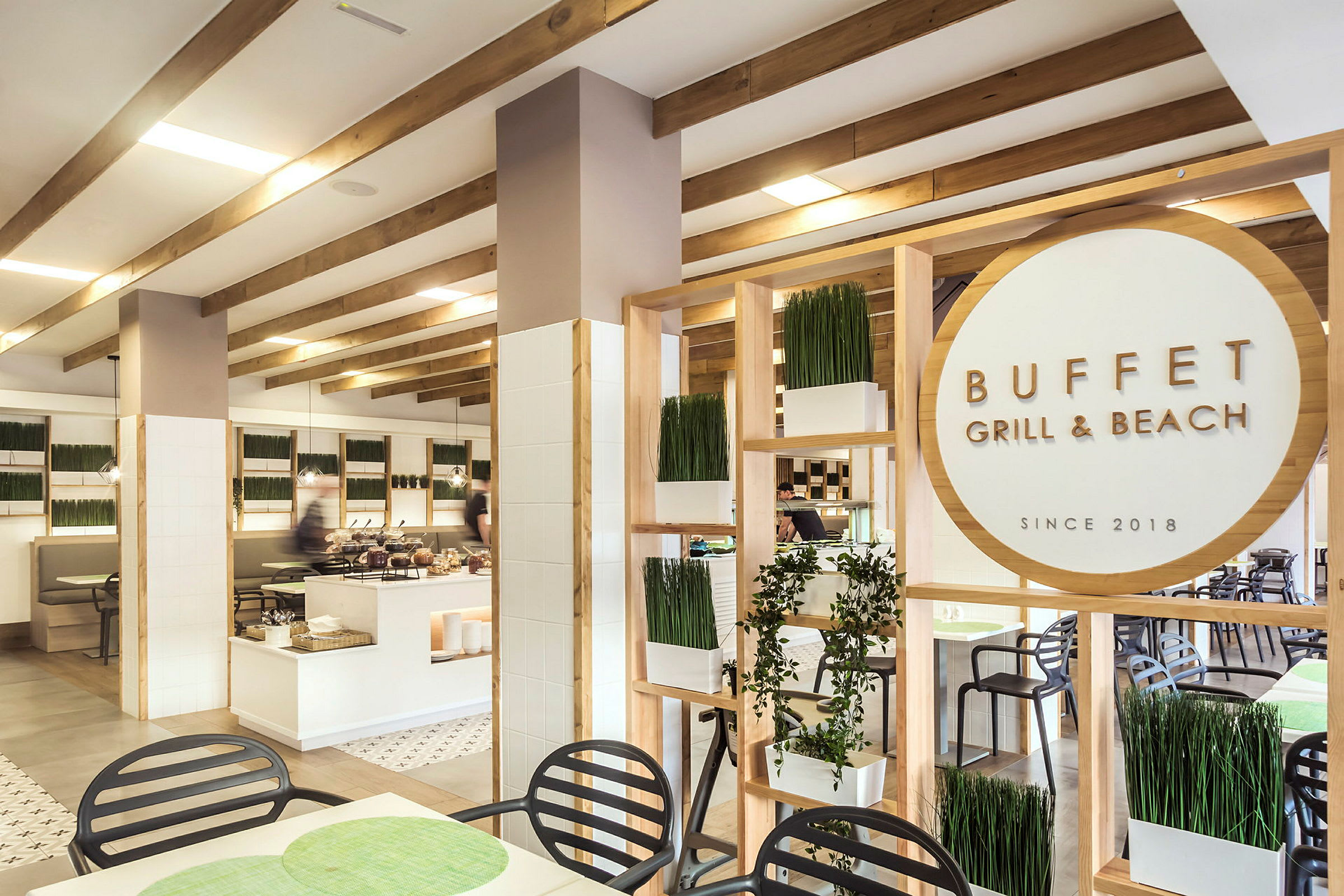 Interiør av en restaurant med buffet, med treverk, plantepynt og et skilt med teksten "Buffet Grill & Beach". (AI-generert tekst)