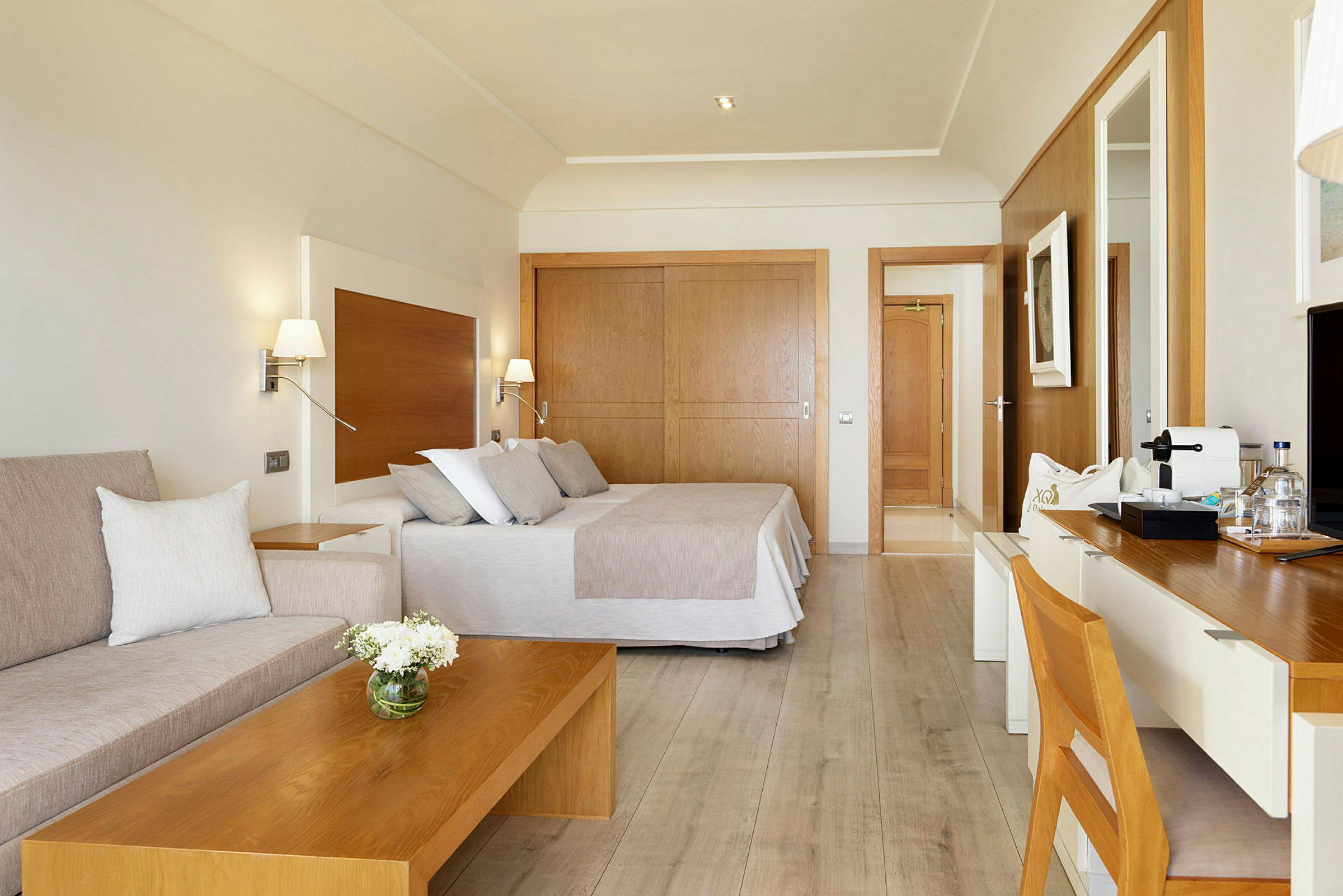 Et hotellrom med moderne innredning, seng, sittegruppe og skrivebord. (AI-generert tekst)