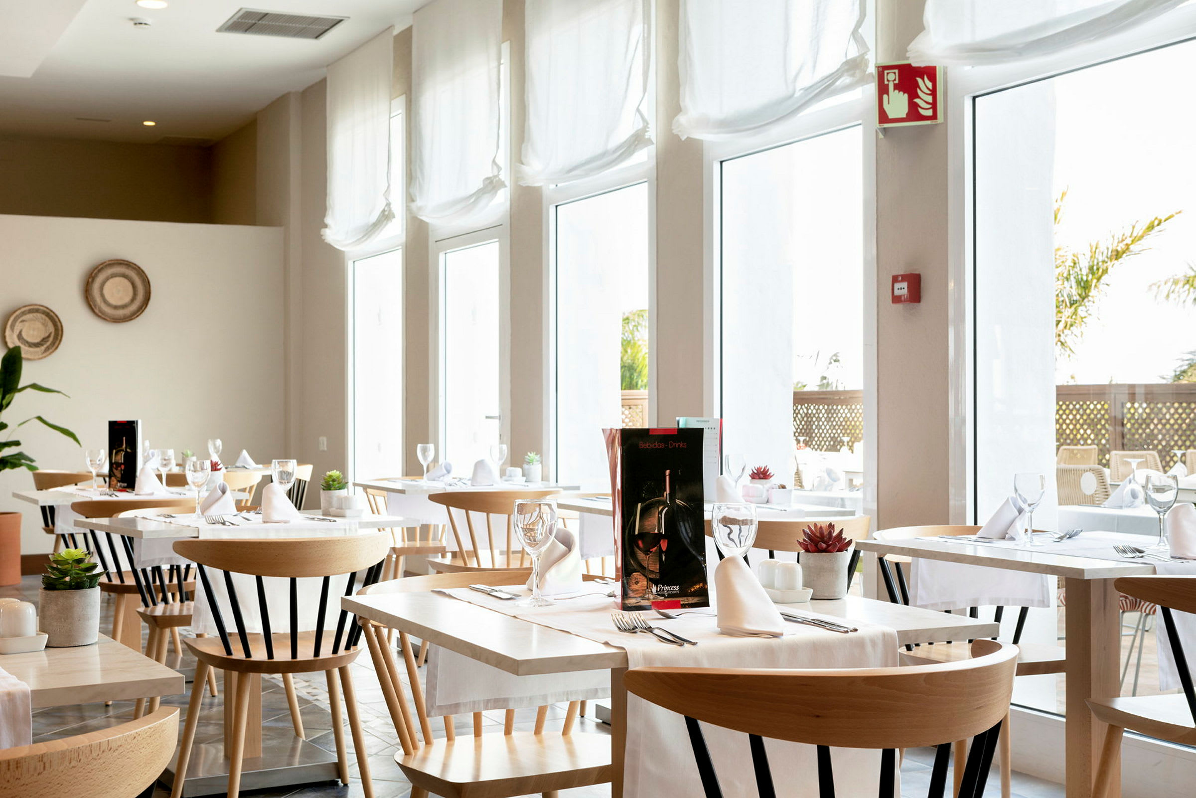 En lys og moderne restaurant med bord og stoler, innredet med hvite duker og glass. (AI-generert tekst)