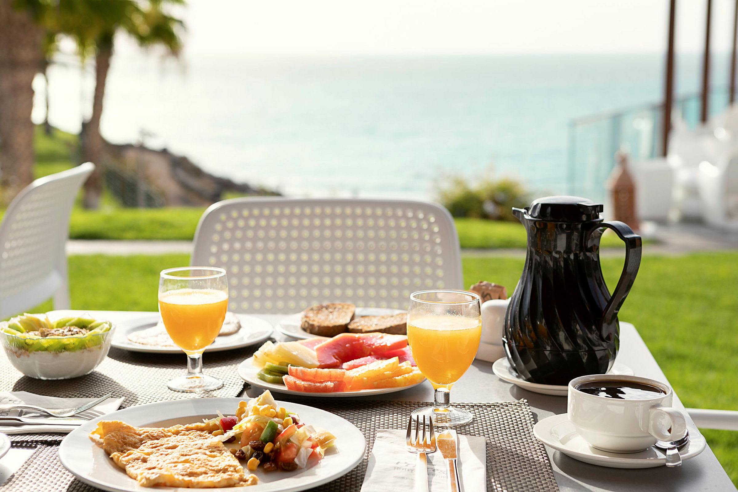 Et bord med frokostmat utendørs, med utsikt mot havet. (AI-generert tekst)
