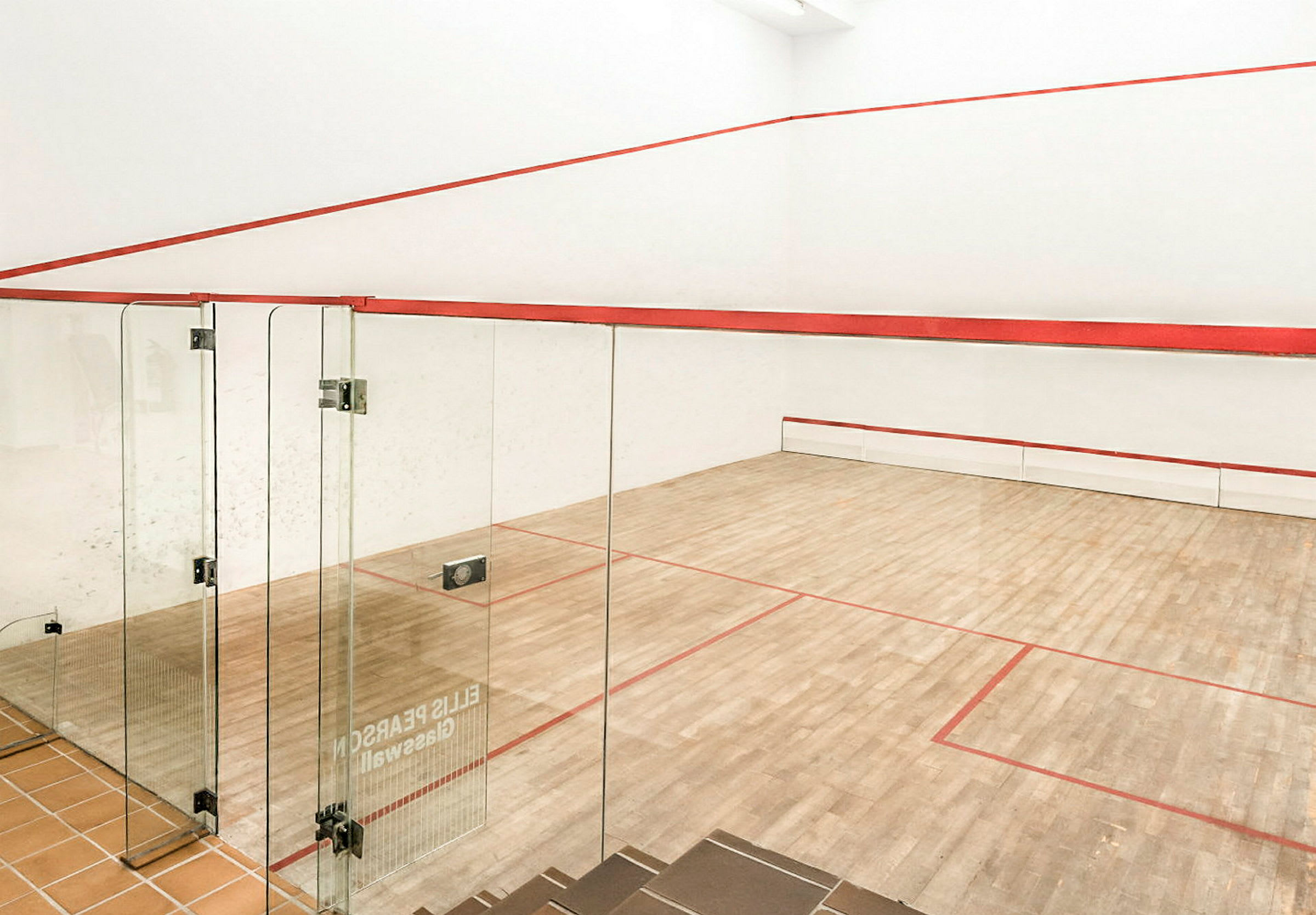 En squashbane med tregulv og glassvegger. (AI-generert tekst)