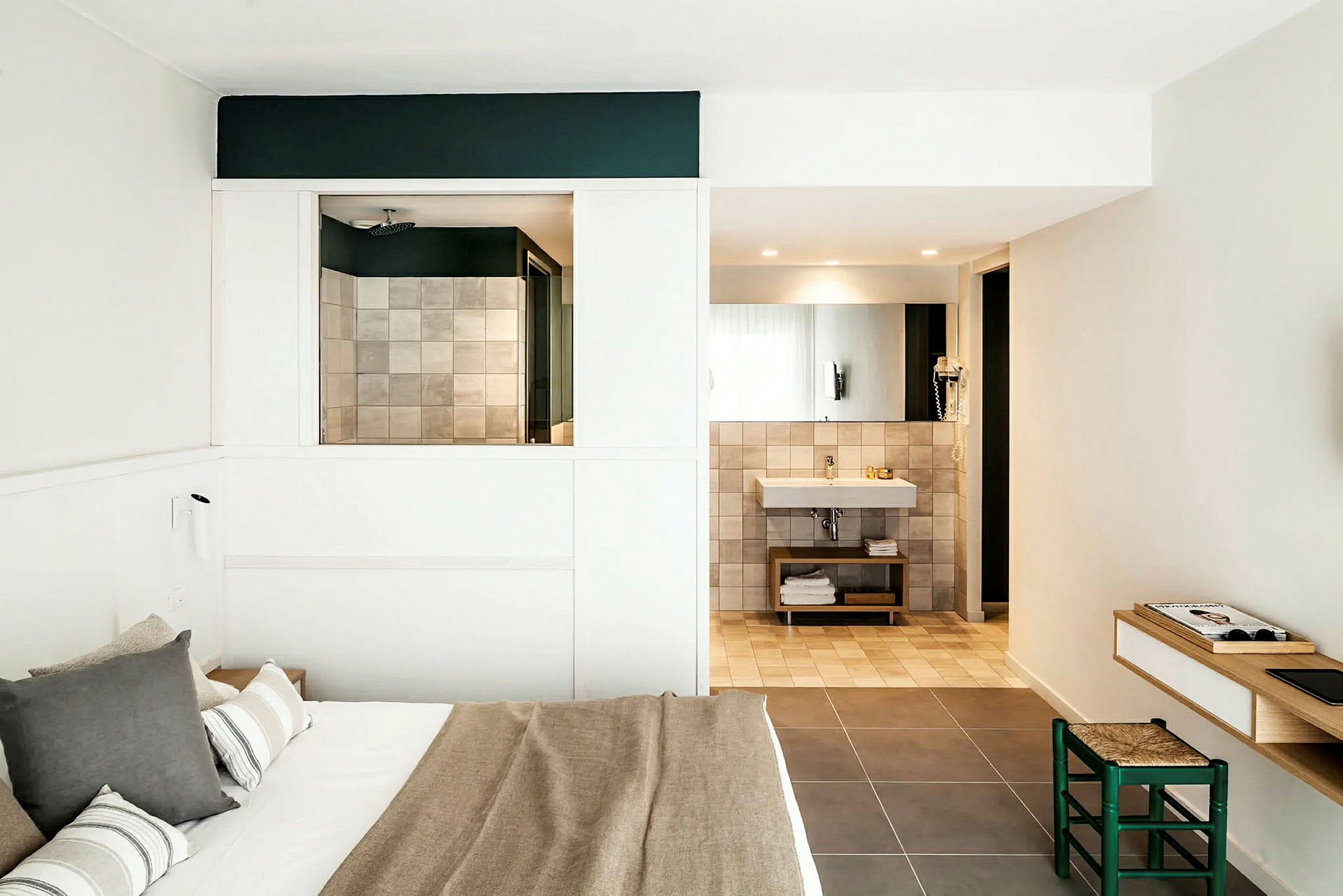 Et moderne hotellrom med en dobbeltseng, bad med speil og vask, samt en liten arbeidsplass med stol. (AI-generert tekst)