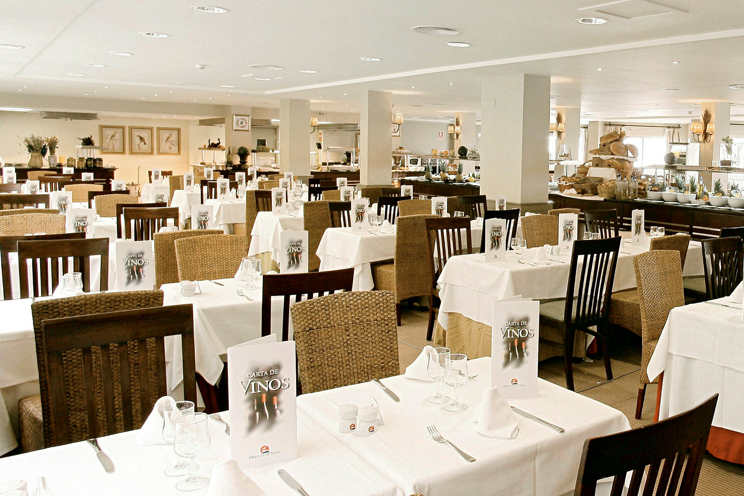 En lys restaurant med dekkede bord og stoler, menyer på bordene og en buffet i bakgrunnen. (AI-generert tekst)