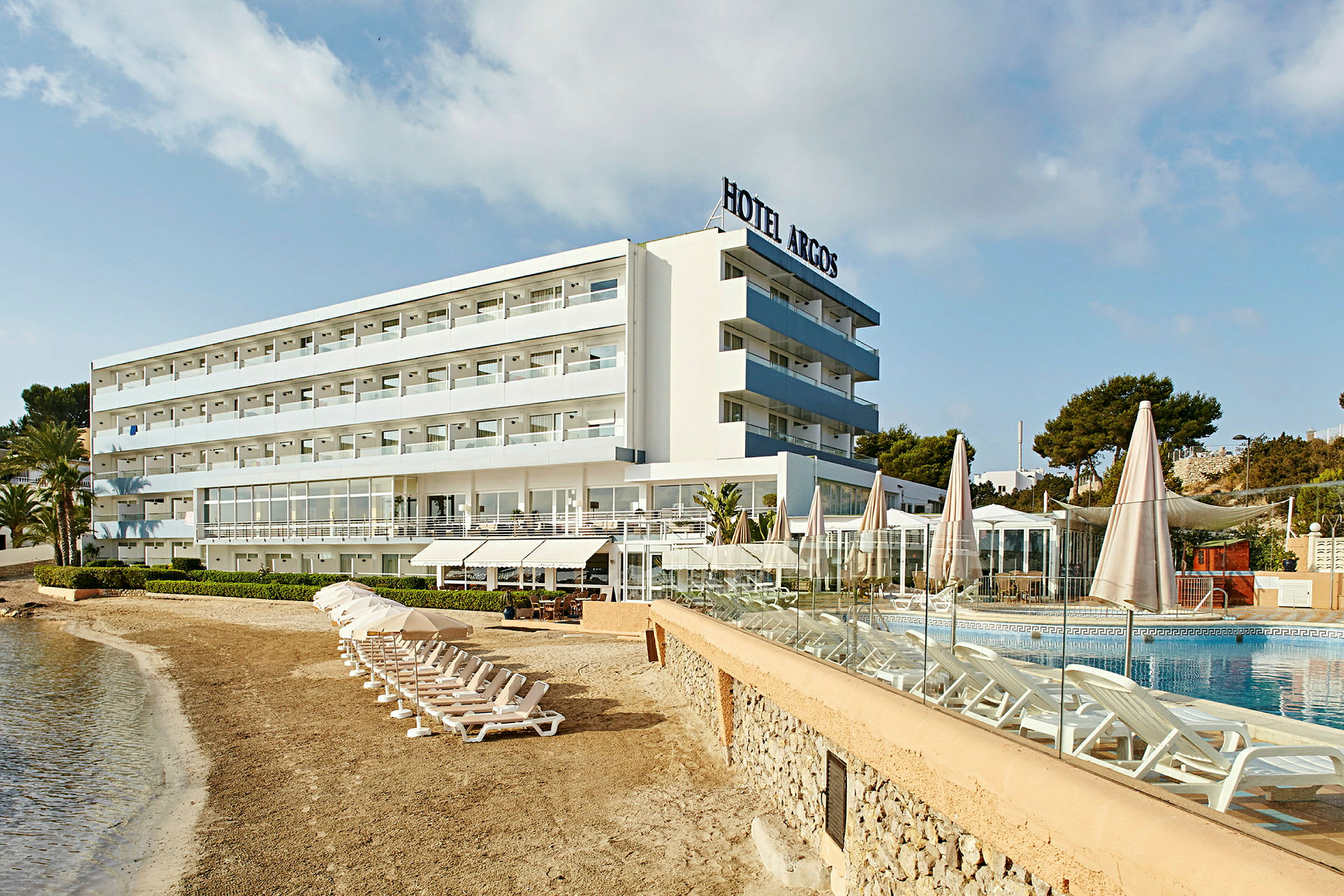 Et hotell ved stranden med solsenger ved bassenget. (AI-generert tekst)