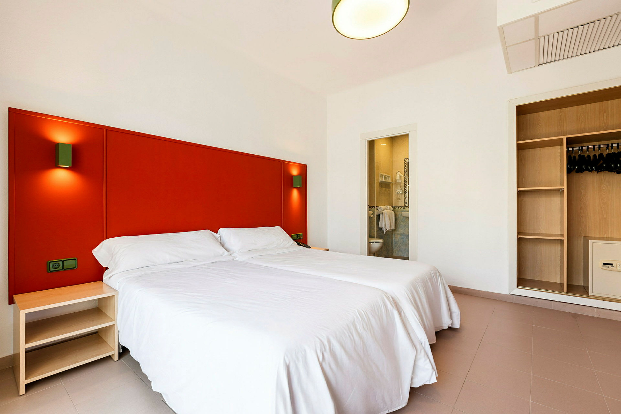 Hotellrom med to enkeltsenger, et skap og et åpent bad. (AI-generert tekst)
