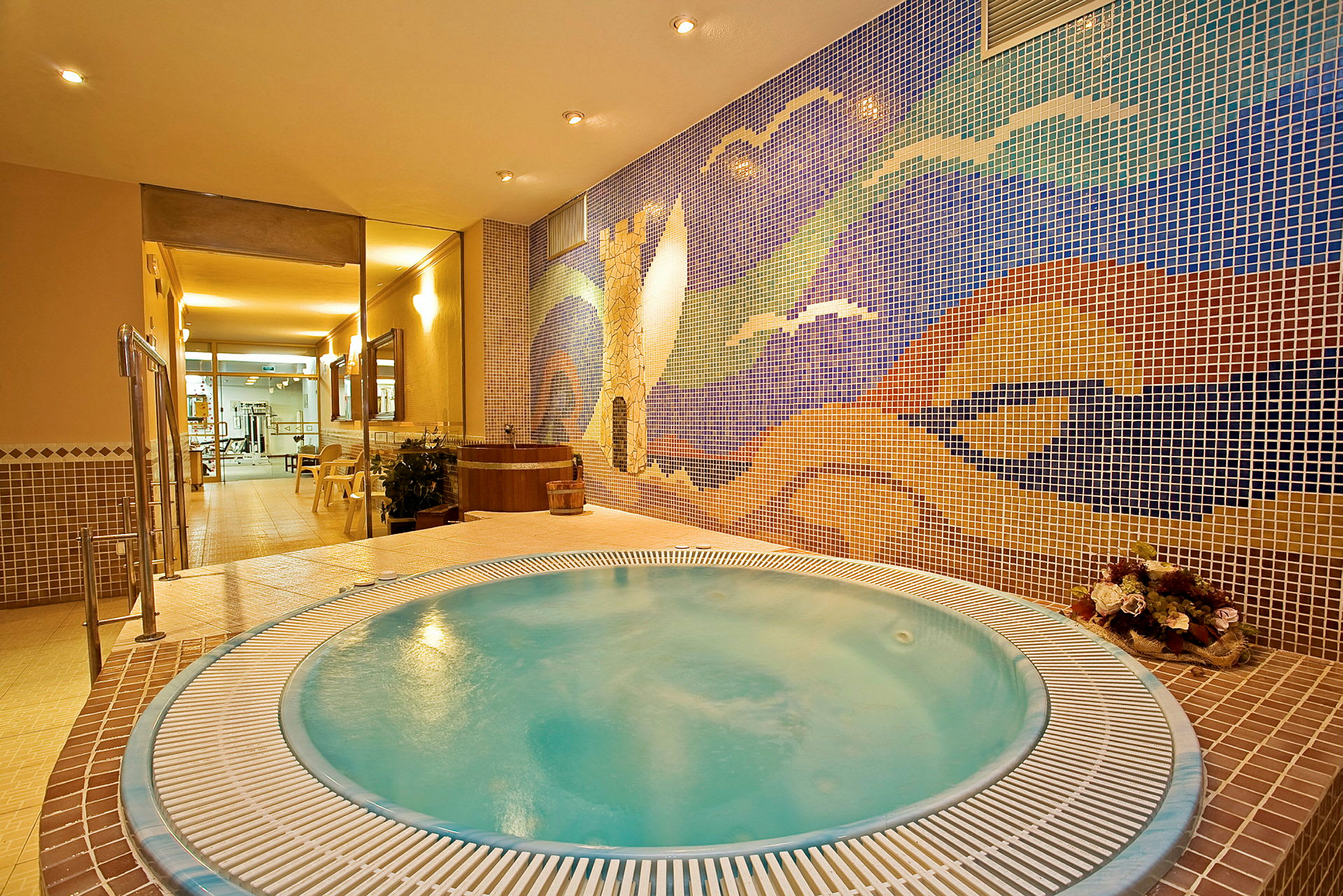 Et boblebad i et spa med en fargerik mosaikkvegg i bakgrunnen. (AI-generert tekst)