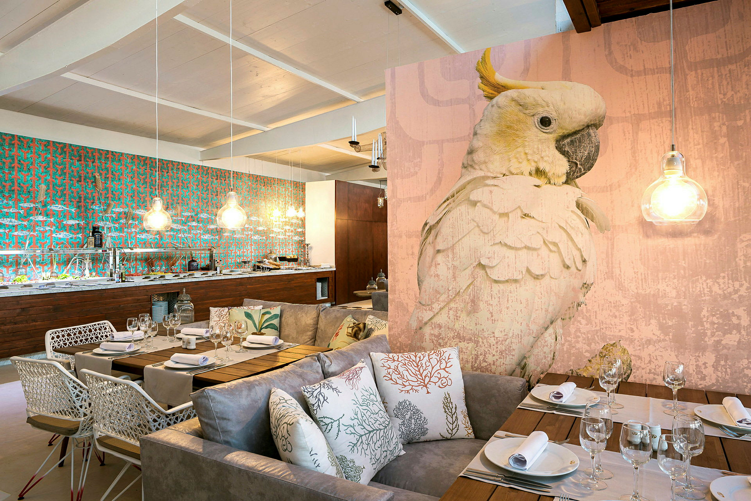 En elegant innredet restaurant med et stort fuglemotiv, dempet belysning og et spiseområde med sofaer og puter. (AI-generert tekst)